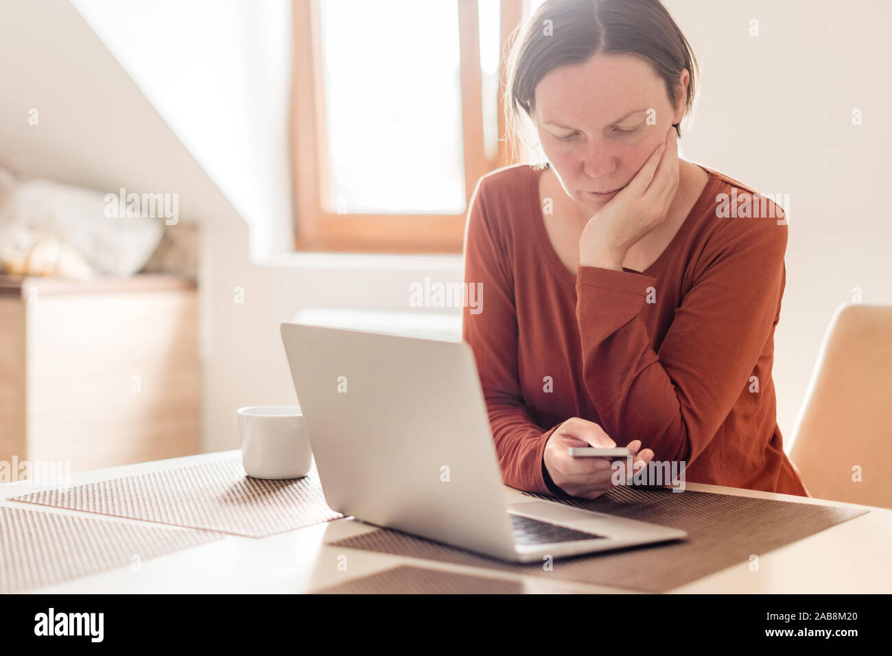 Woman telecommuting in home office interior. Portrait of female freelancer using mobile phone, selective focus. Stock Photo