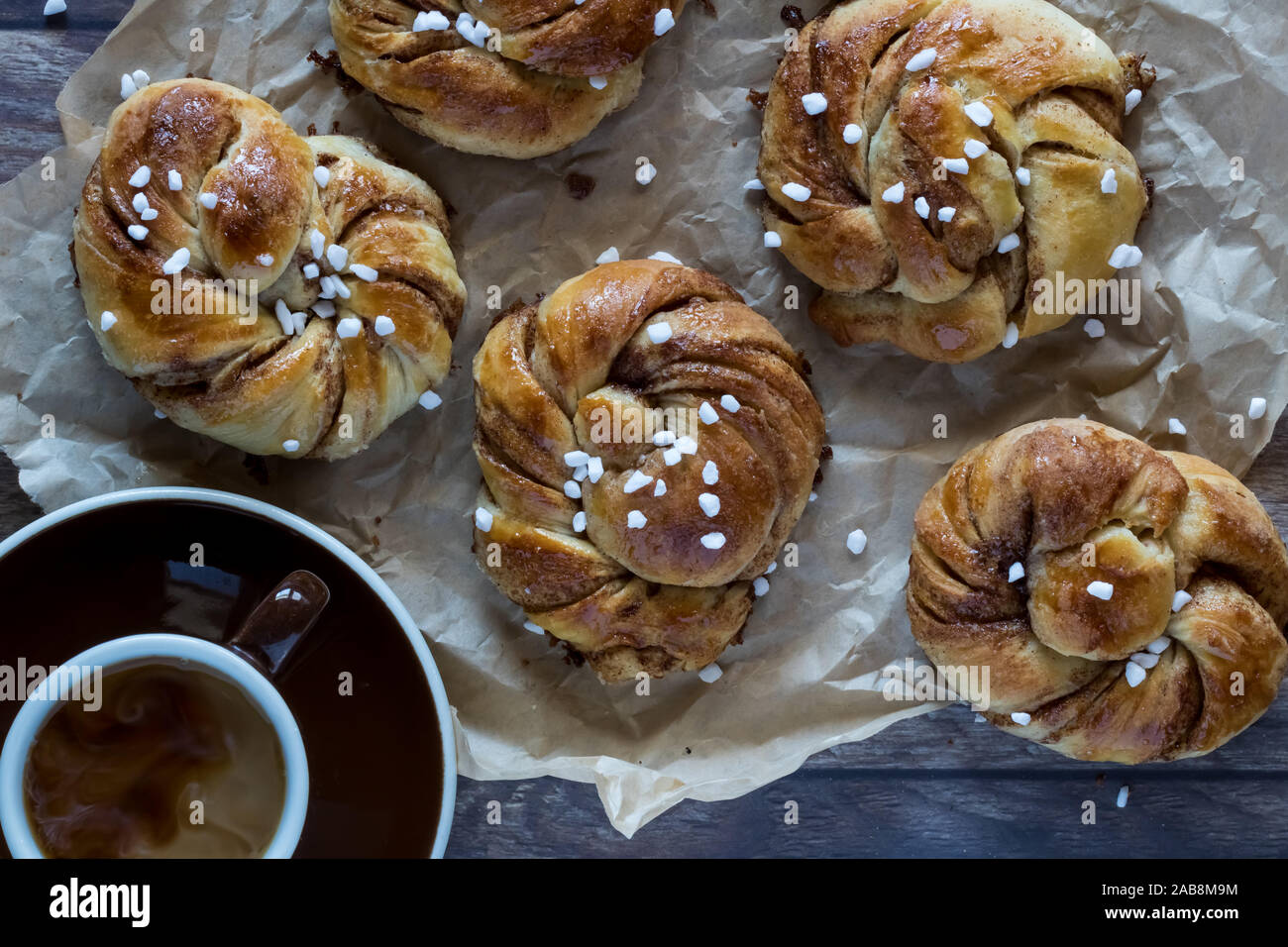 Top down view of Swedish cinnamon buns on parchment paper and a cup of ...