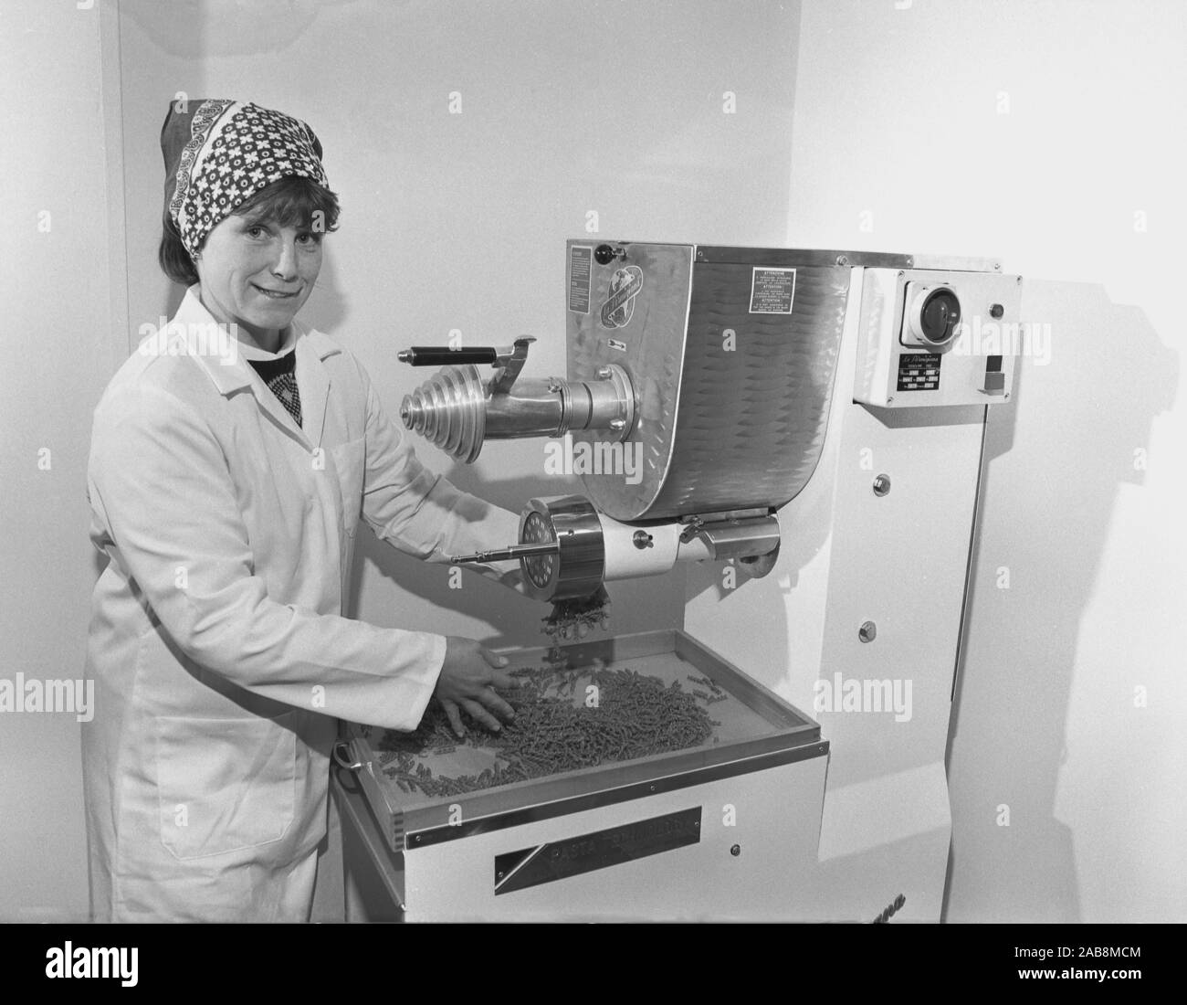 1980s, historical, a lady worker in overalls working with an Italian made machine at a food factory, making pasta, fusilli, Yorkshire, England, UK. Stock Photo