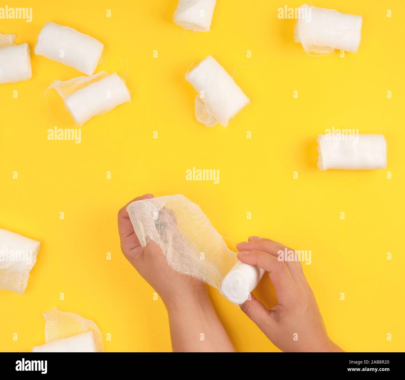 hand wrapped with white gauze bandage, yellow background, top view
