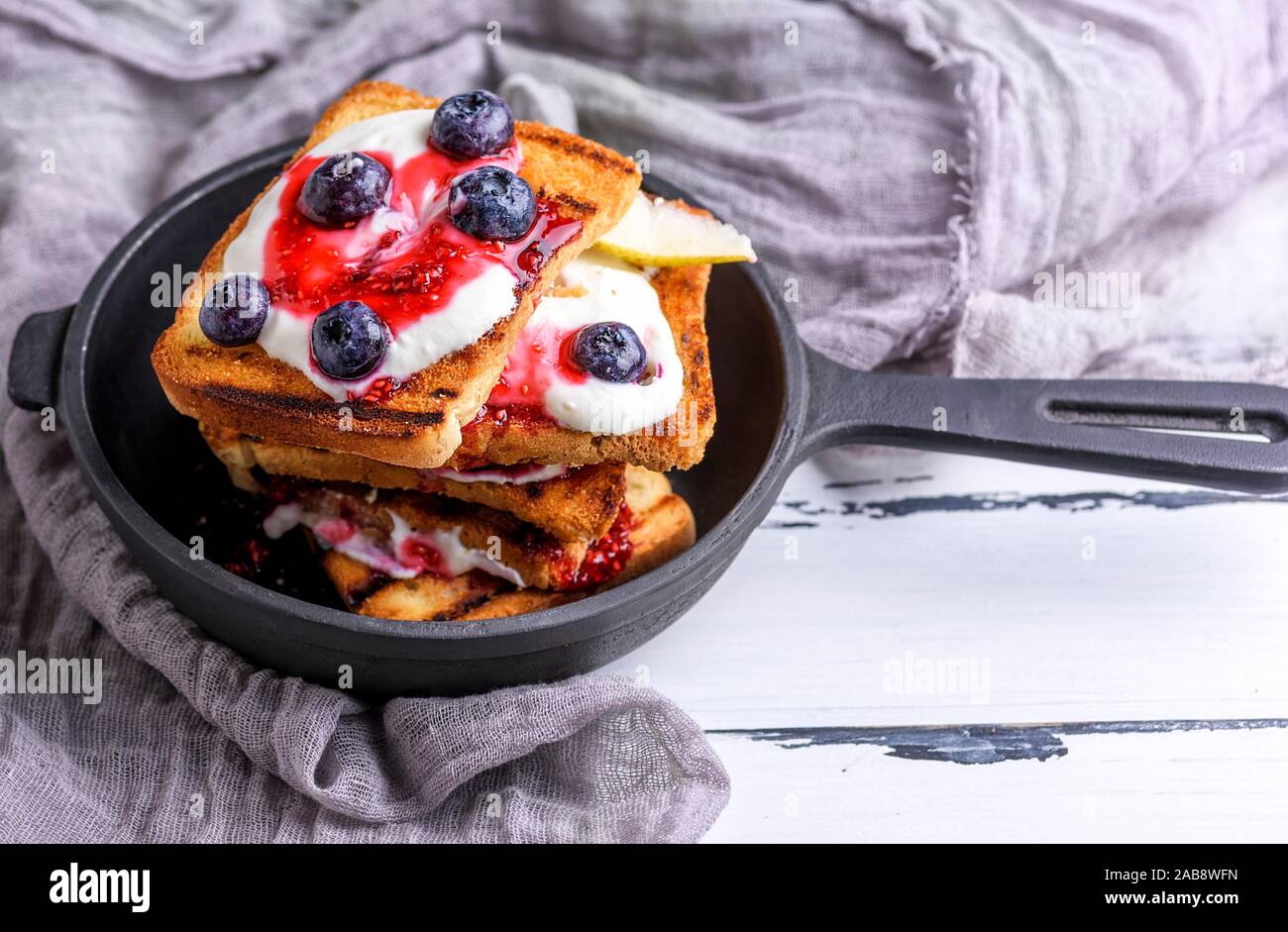 French Toast With Berries Syrup And Sour Cream In A Black Cast Iron Frying Pan Top View Stock Photo Alamy