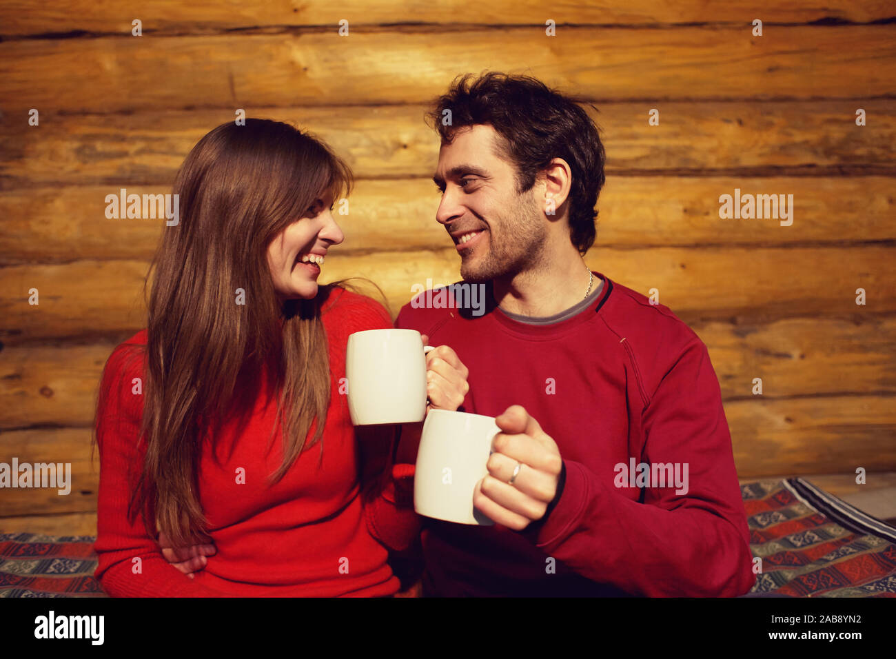 man and woman drinking tea at home. young couple in love with mugs in hands Stock Photo