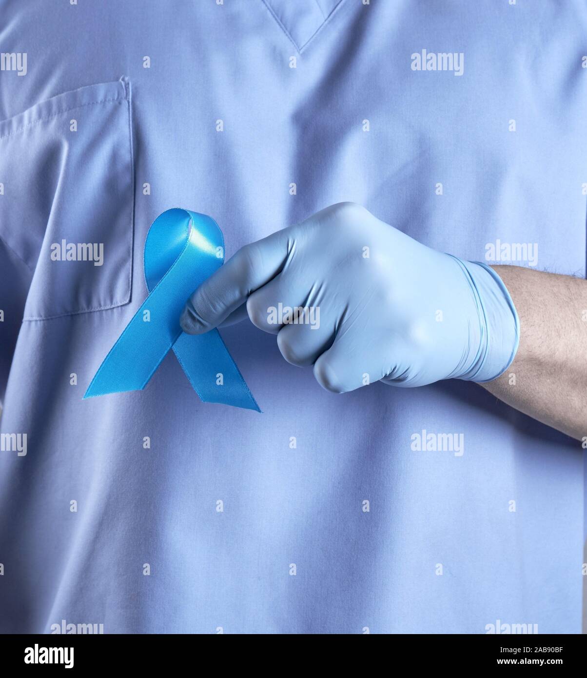 doctor in uniform and latex gloves holding a blue ribbon in his hand, a symbol of the fight and