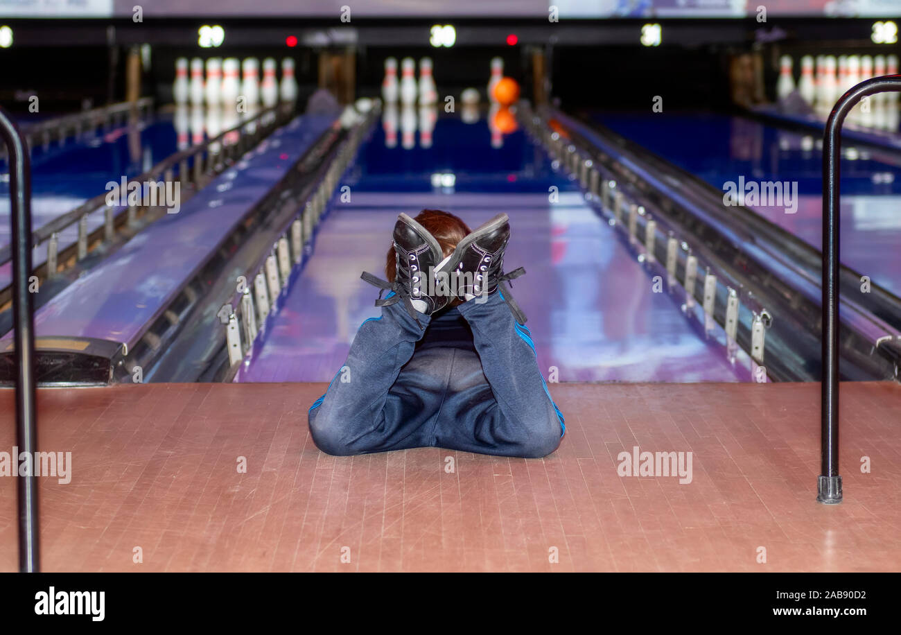 Young Ball Watching Bowling Bowl Roll Down the Lane While Lying on His