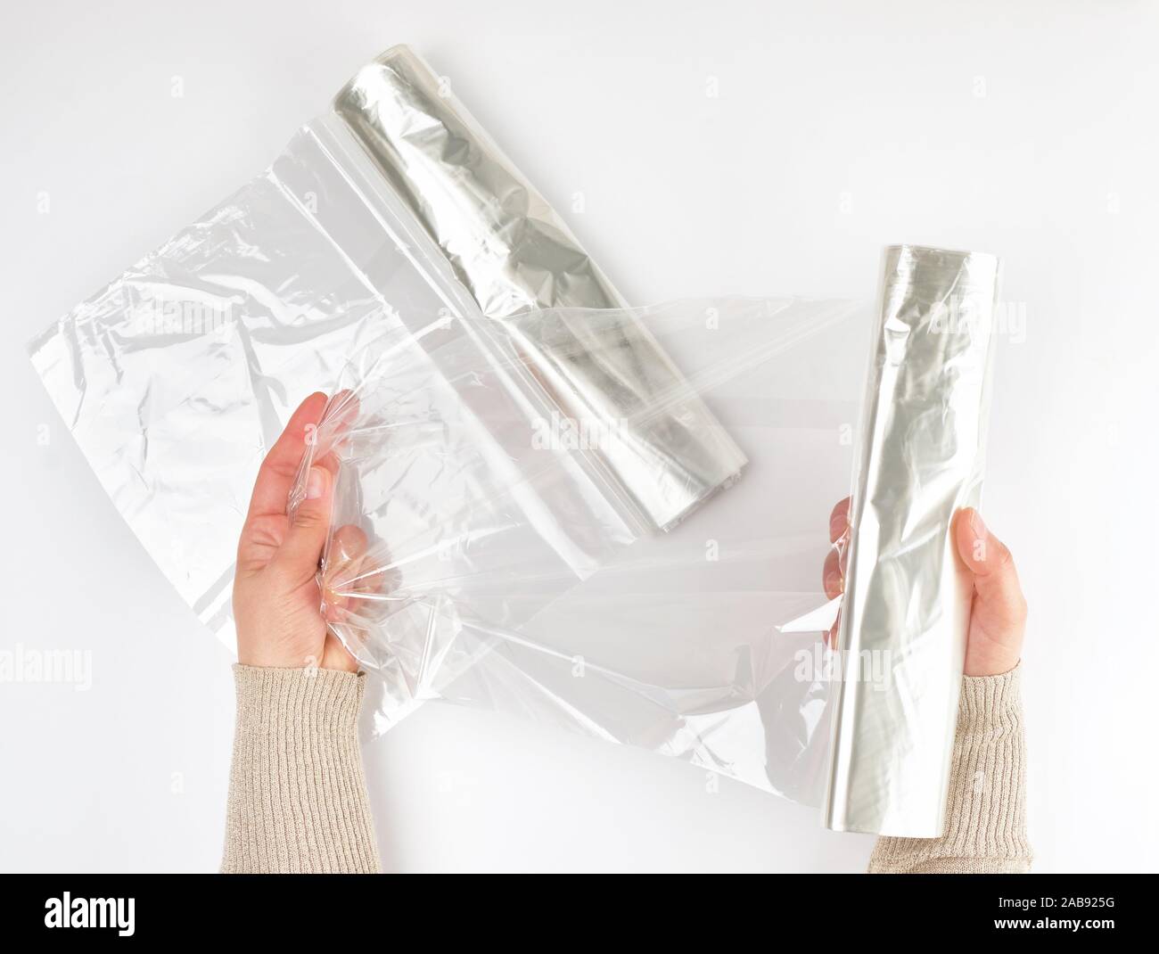 Plastic food wrap for baking products in the oven in women's hand, view from the top, white background. Stock Photo