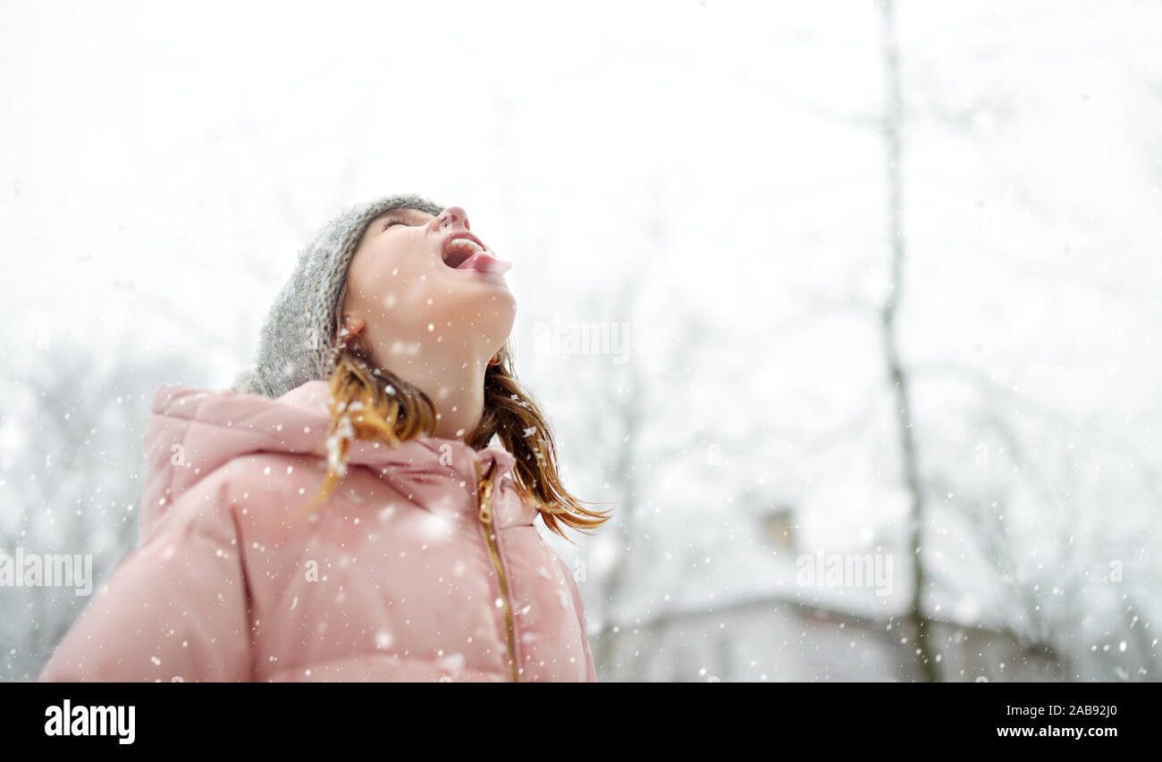 Adorable young girl catching snowflakes with her tongue in beautiful ...
