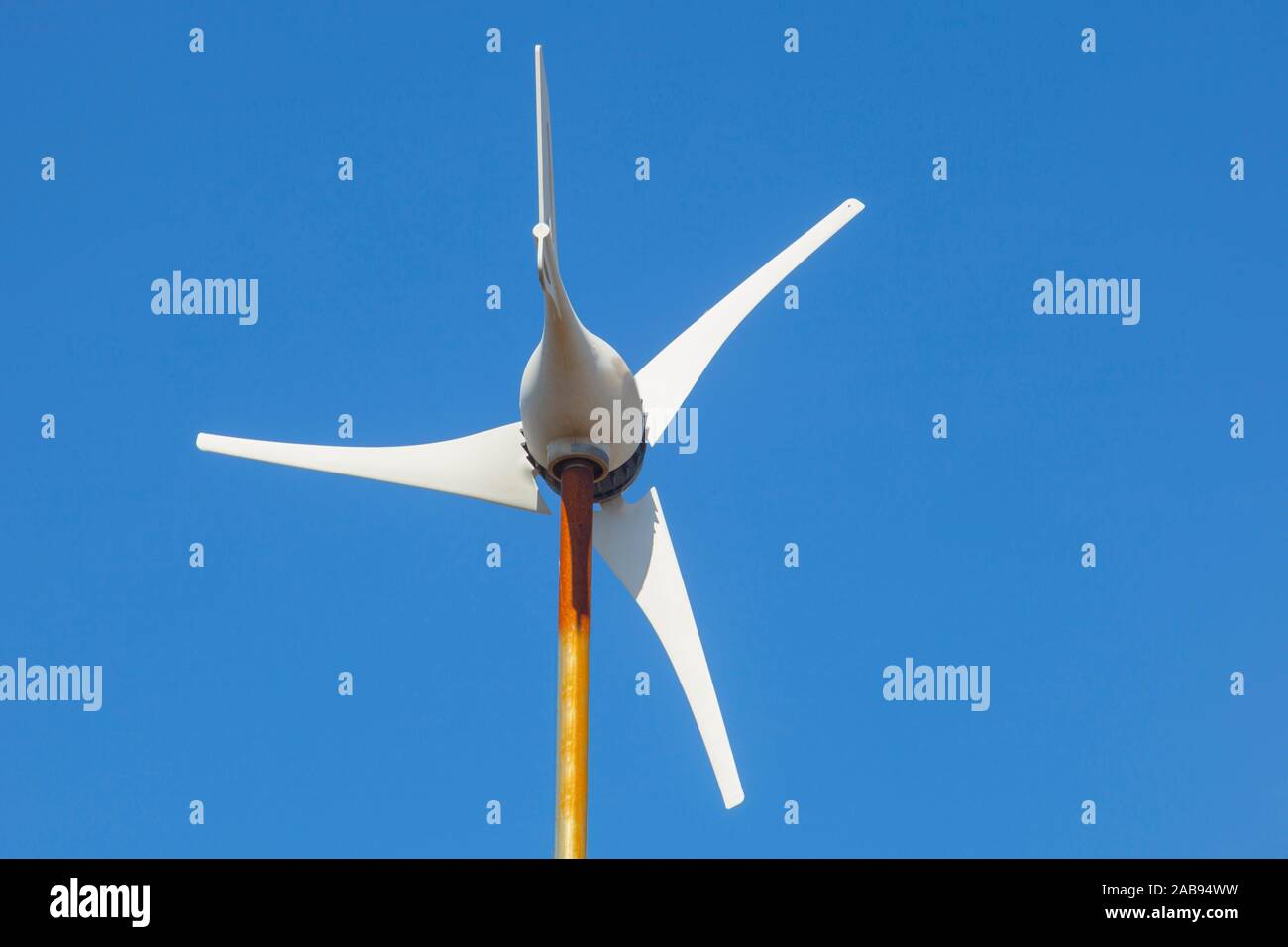 Domestic Wind Turbine mounted over metalic pole. Blue sky background. Stock Photo