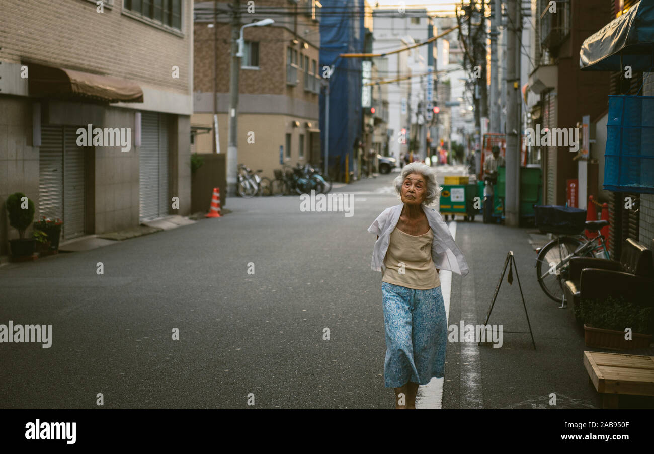 Old woman walks on a street in Asakusa, Tokyo, Japan.  Japan's birth rate is declining and the population is aging. Stock Photo