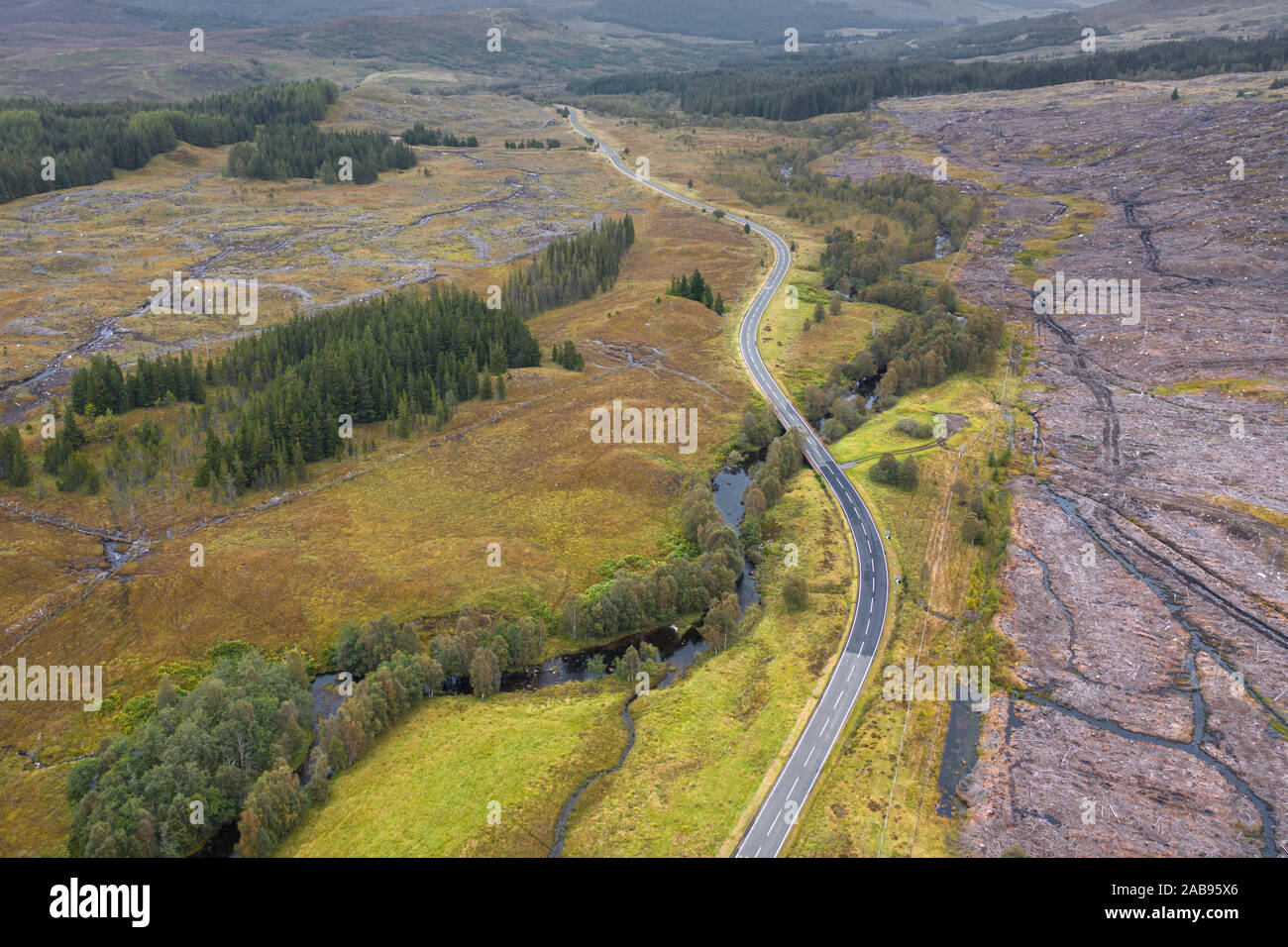 Drone shoot at cloudy autumnal morning over empty asphalt road A87 near Loch Loyne in in the Northwest Highlands of Scotland along North Coast 500 Stock Photo