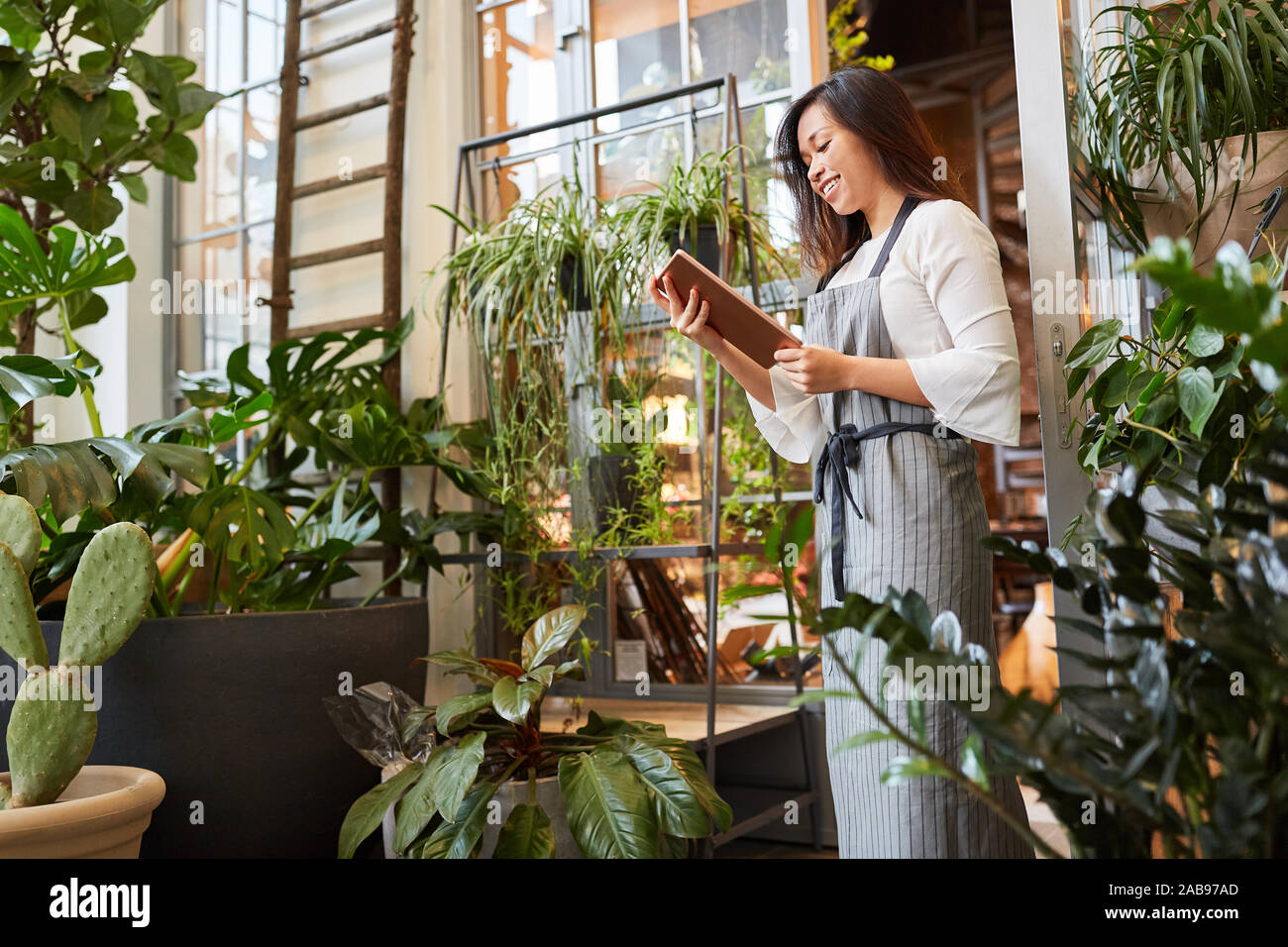 Smiling Florist with Tablet PC is pleased about an order online Stock Photo