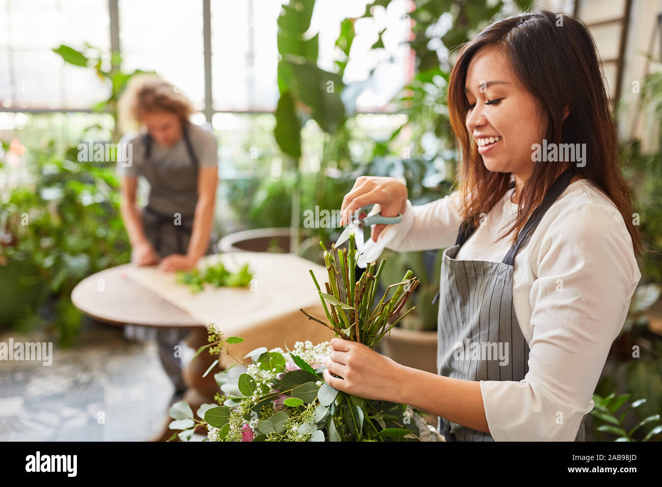Asian florist with pair of scissors while bouquet tying in the flower shop Stock Photo