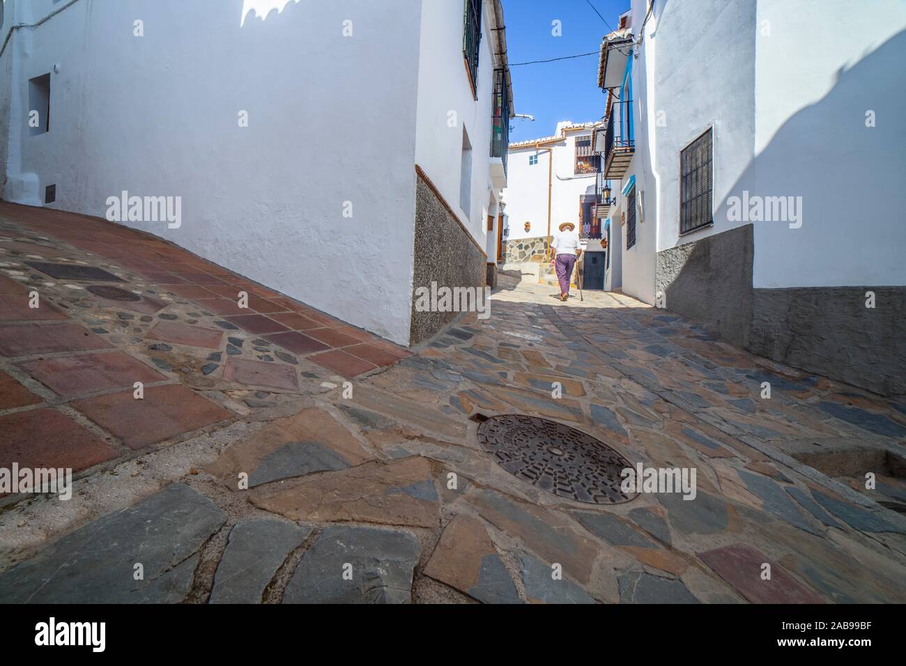 Elderly local man climbing slope narrow street of Comares, Malaga, Spain. White village up on the hill of Malaga mountains, also called Axarquia Stock Photo