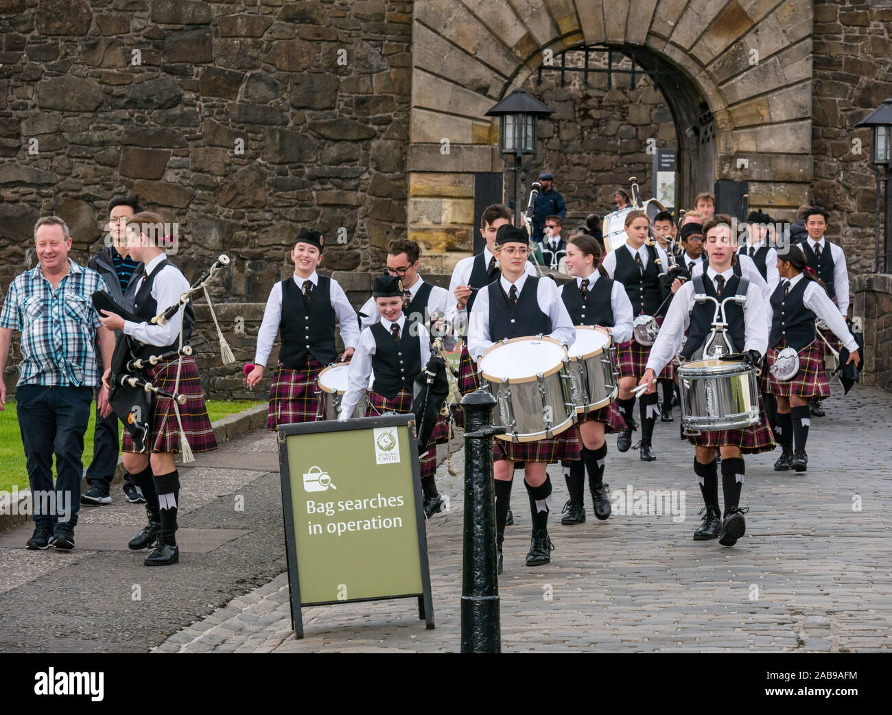 Youths or teenagers from school pipe band with drums and bagpipes wearing matching kilts, entrance gate of Stirling Castle, Scotland, UK Stock Photo