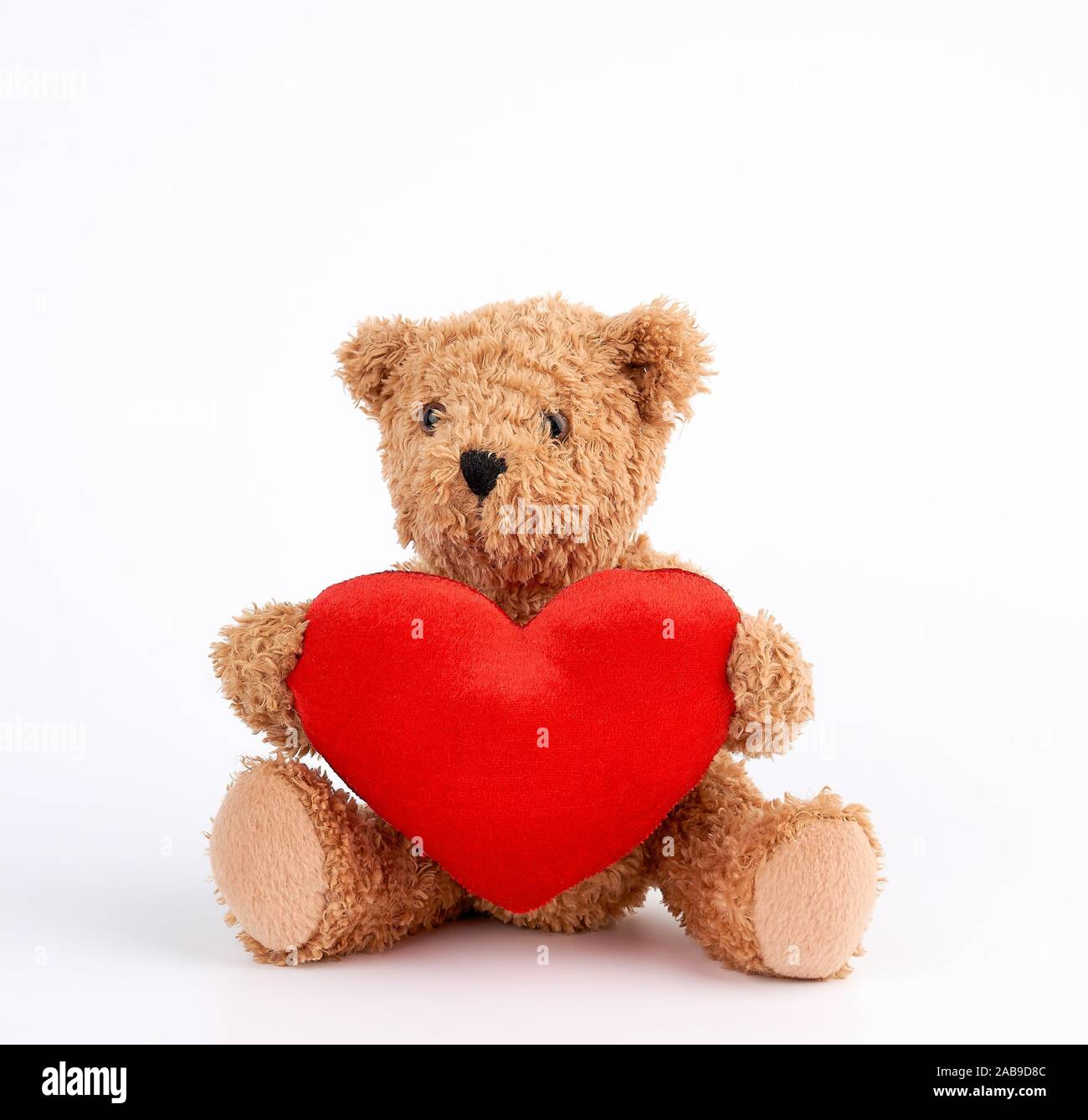 cute brown teddy bear holding a big red heart on a white