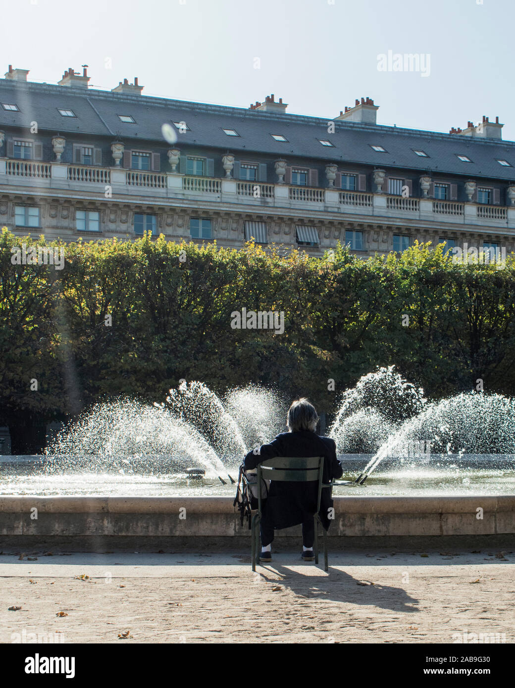 Man sitting enjoying the fountain in the Jardin du Palais Royal Stock Photo
