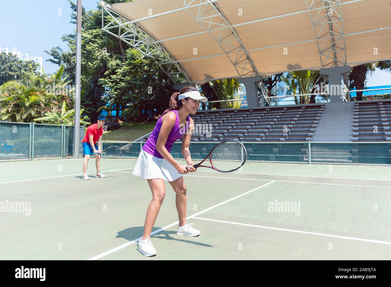 Confident female tennis player waiting to hit the ball during doubles match Stock Photo