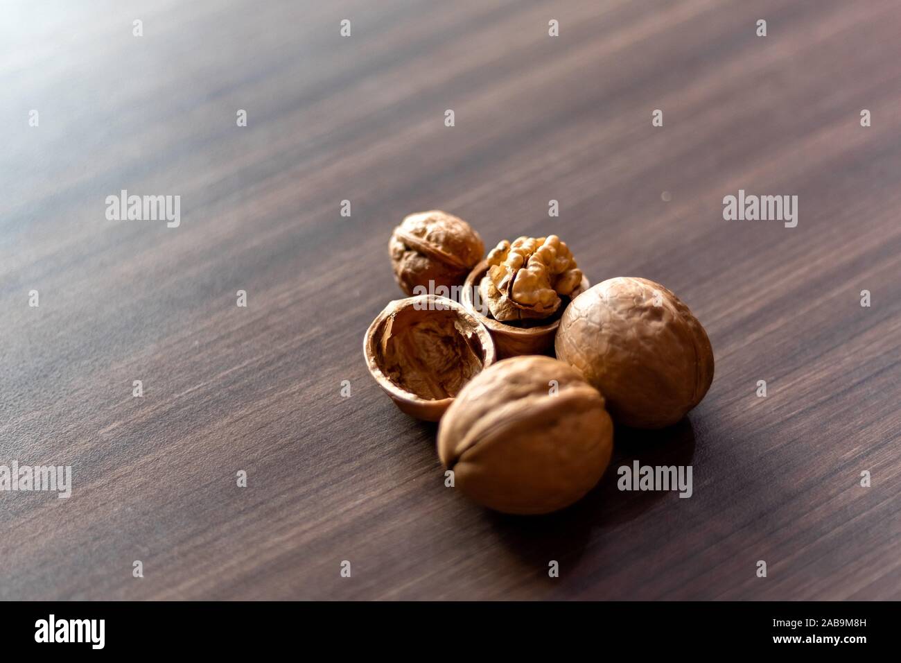 Walnuts kernels on wooden desk with color background, Whole walnut in wood vintage bowl. Stock Photo