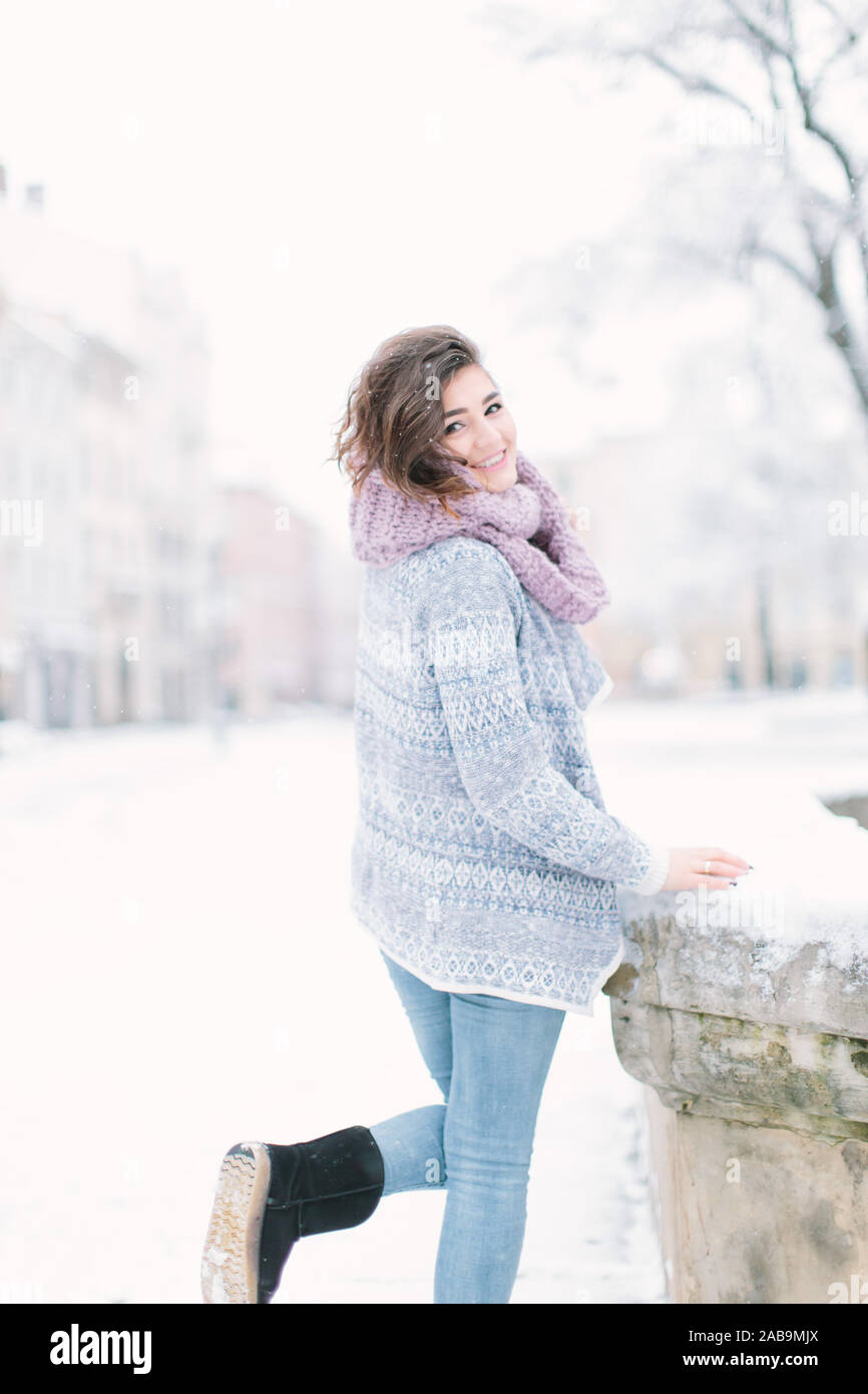 Outdoor portrait of young beautiful happy smiling girl posing on street.  Model wearing stylish warm clothes. Magic snowfall. Christmas, new year  Stock Photo - Alamy
