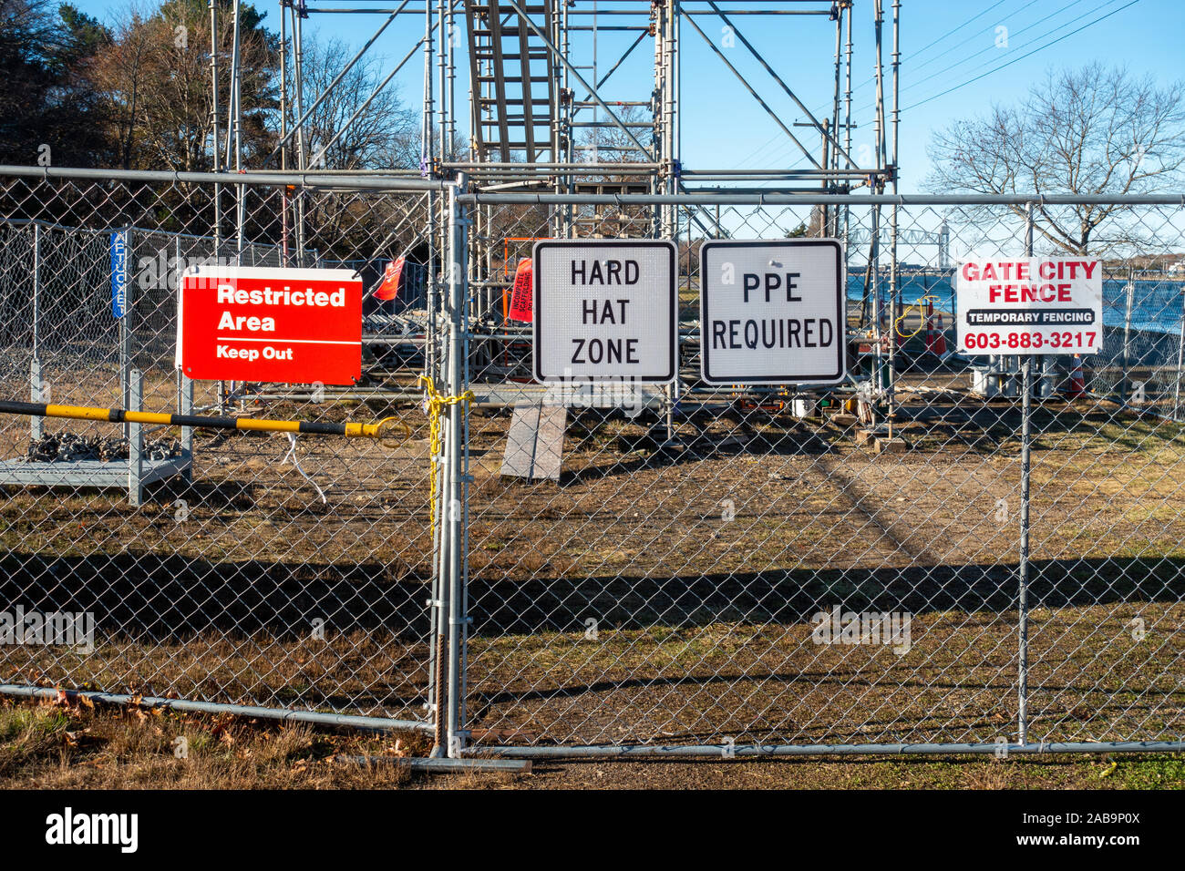 Restricted Area Keep Out, Hard Hat Area, PPE Required signs on chain link fence at construction site by Gate City Fence Temporary Fencing Stock Photo