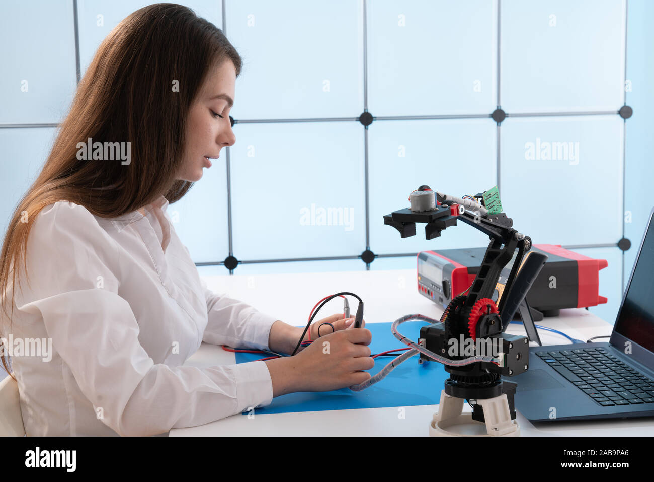 A young woman writes an algorithm for the robot arm. Science Research ...