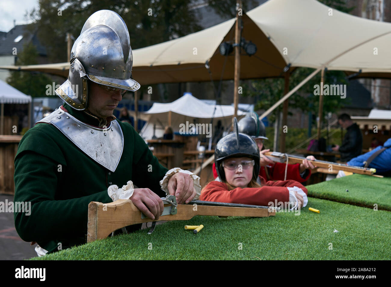 A participant dressed as a soldier teaches children how to use a toy musket. Stock Photo