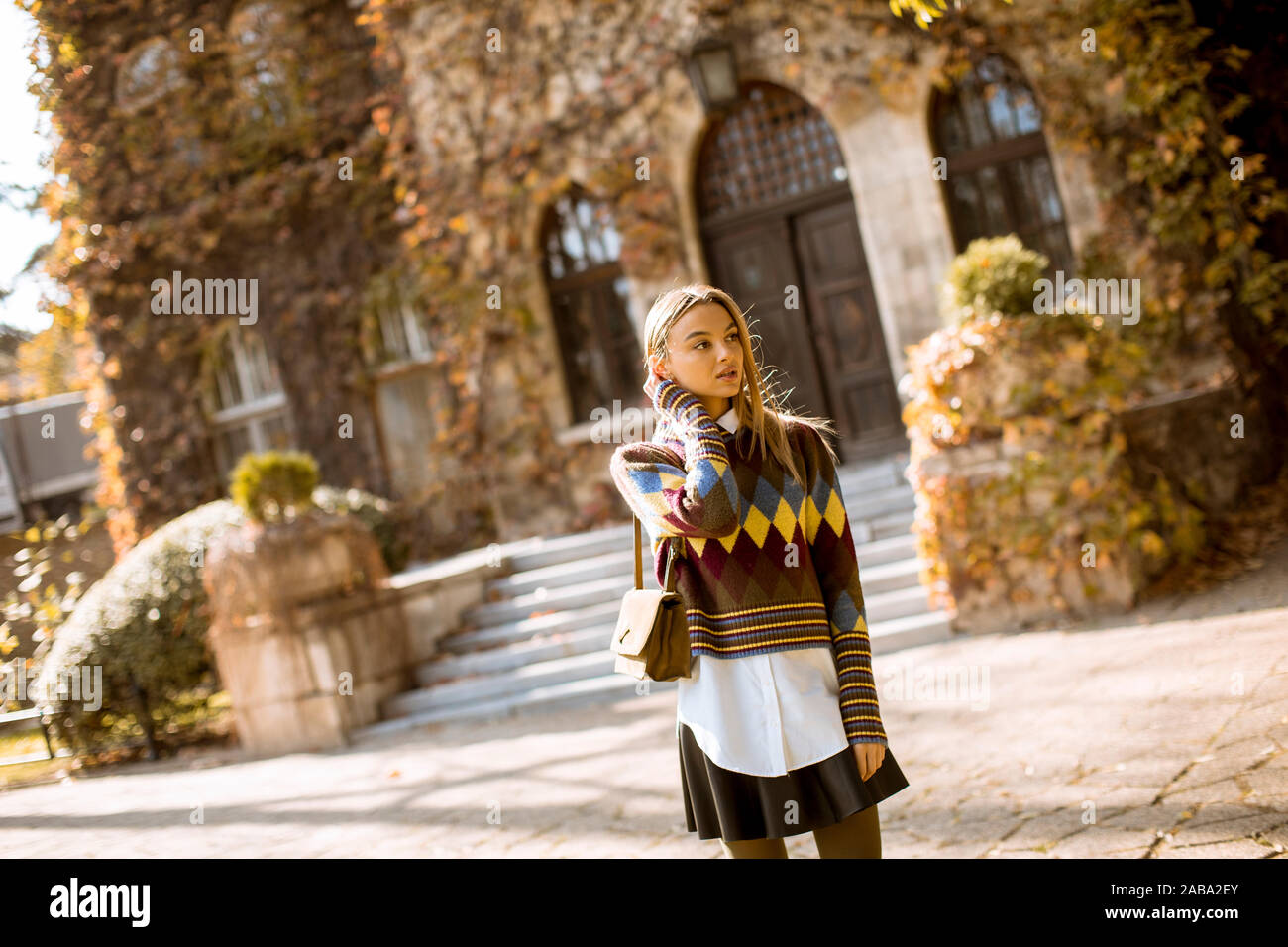 Pretty young woman standing outside at sunny autumn day Stock Photo