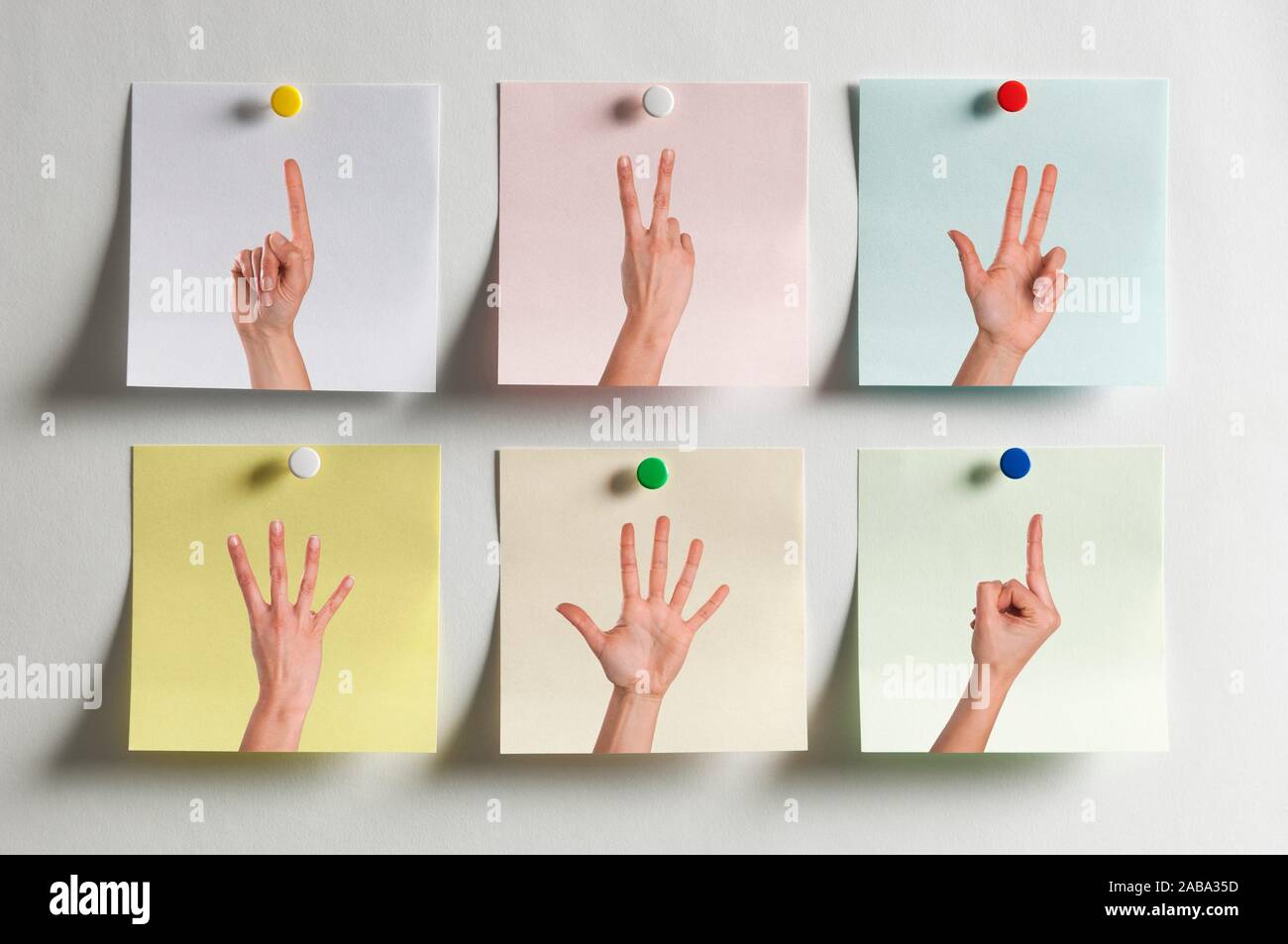 Five colorful Post It messages fixed to the wall with images of fingers  indicating numbers and one with the middle finger Stock Photo - Alamy