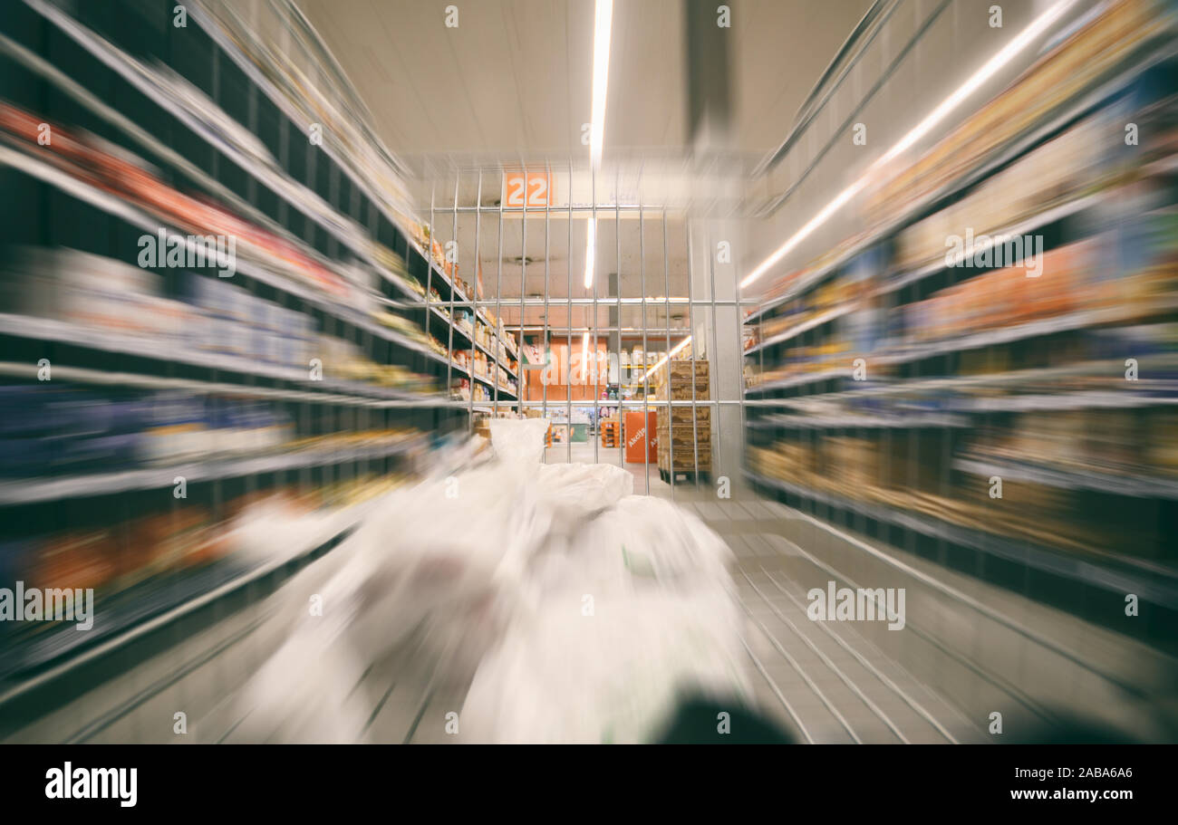 Shopping cart with groceries moving through supermarket, shopping concept. Stock Photo
