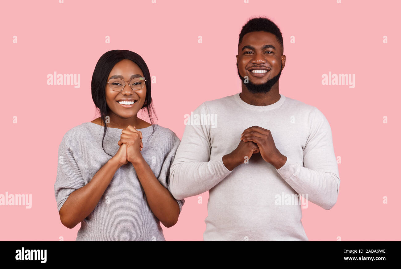 Emotional black couple expressing hope over pink background Stock Photo
