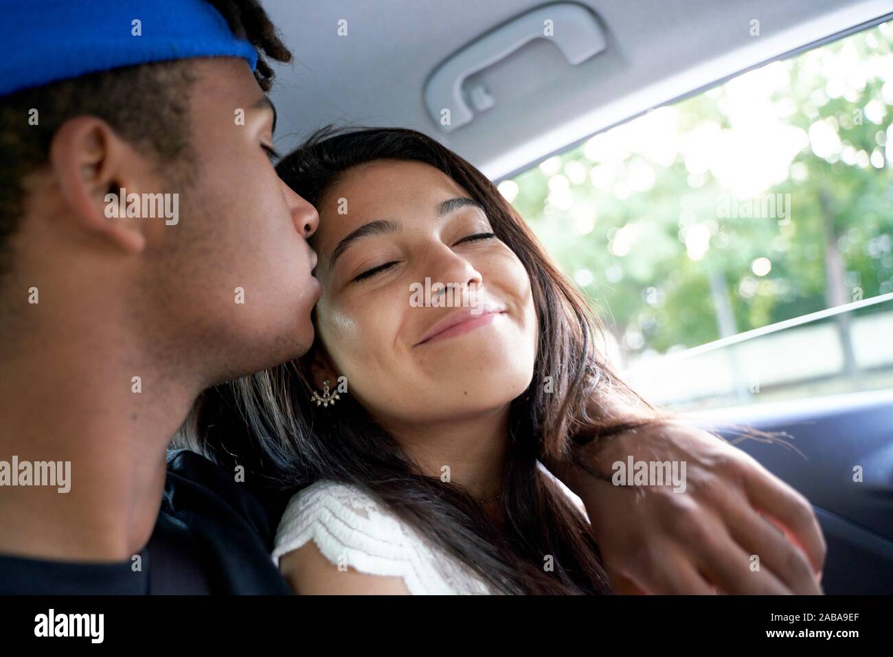 Young couple sitting together in the back seat of car. Stock Photo