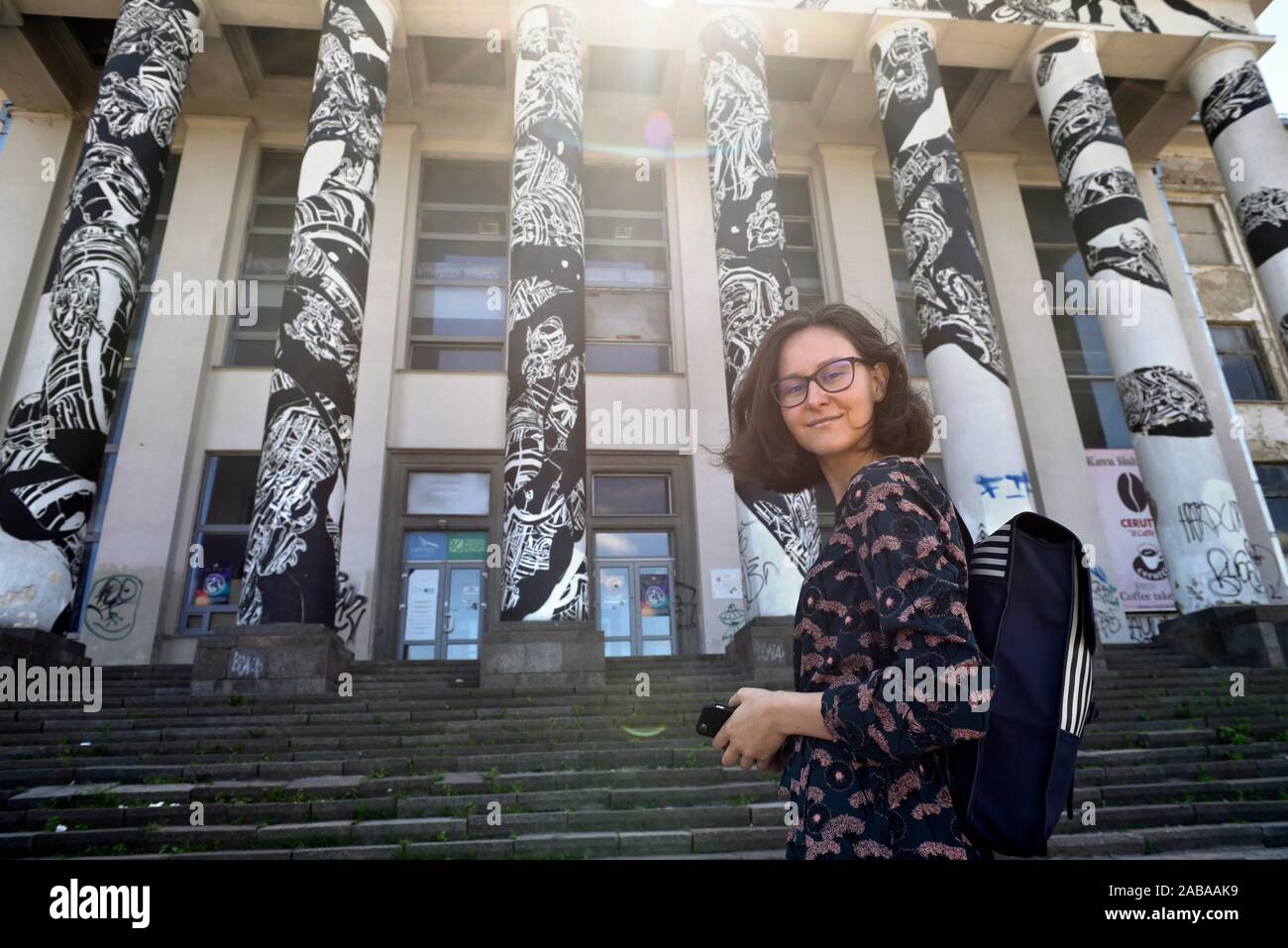 young woman posing in front of the columns of former disused palace of the Soviet period on Tauras Hill, Vilnius, Lithuania, Europe. Stock Photo