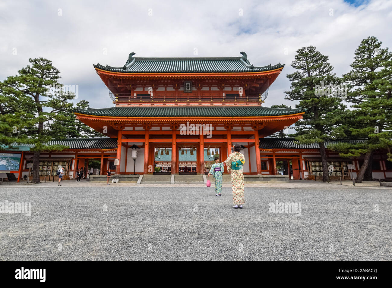 Two young Asian tourists dressed in traditional japanese kimonos taking a photo in front of the famous Heian Shrine in Kyoto, Japan. Stock Photo