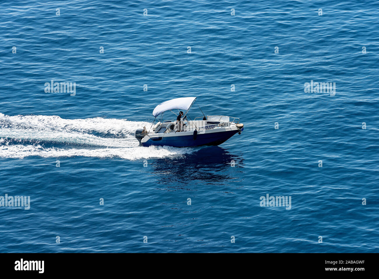 Vernazza, small motor boat with one person runs fast in the blue Mediterranean sea with white wake, from above. Cinque Terre, Liguria, Italia, Europe Stock Photo