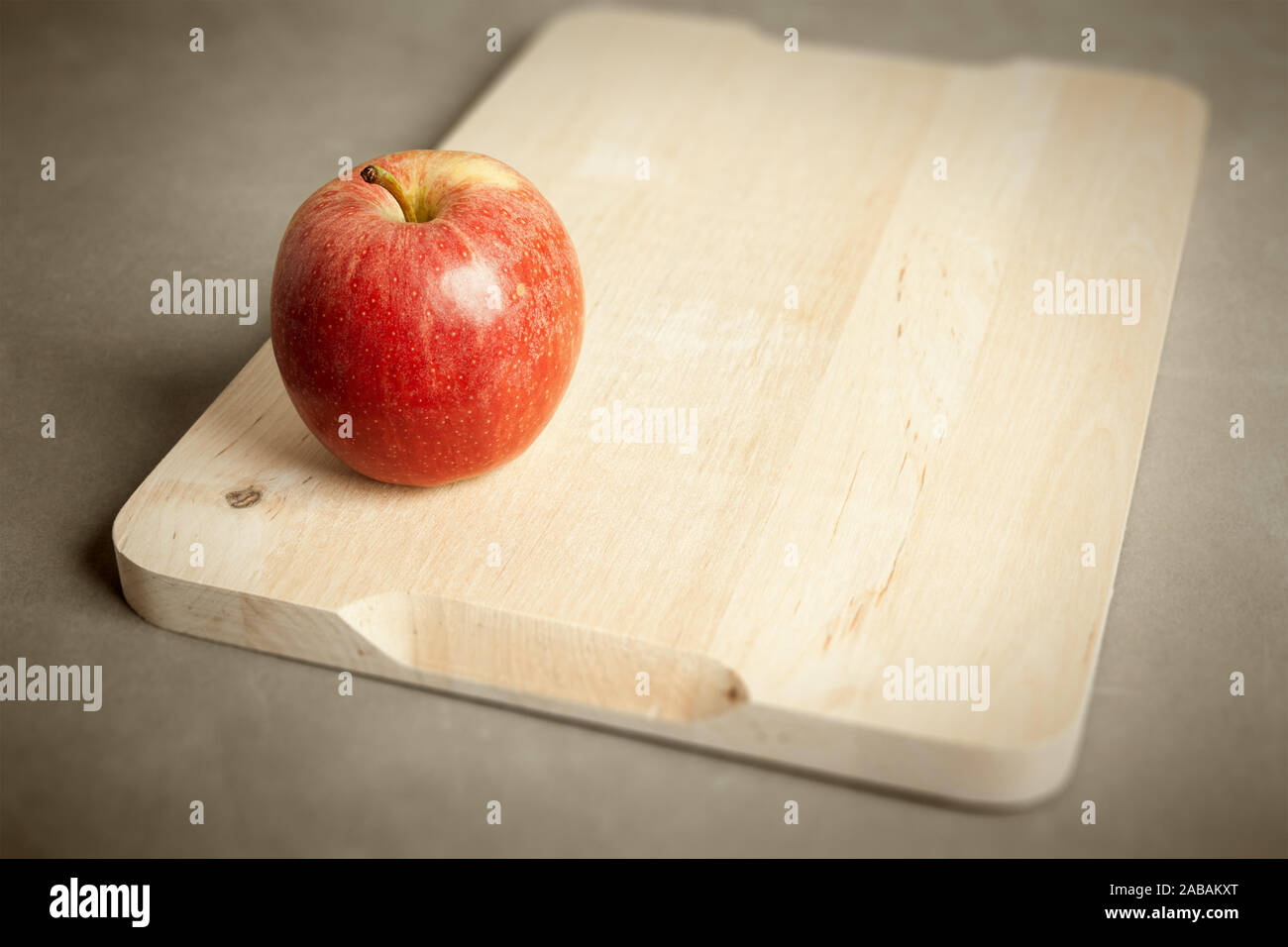 Ein roter Apfel auf einem hölzernen Schneidebrett Stock Photo