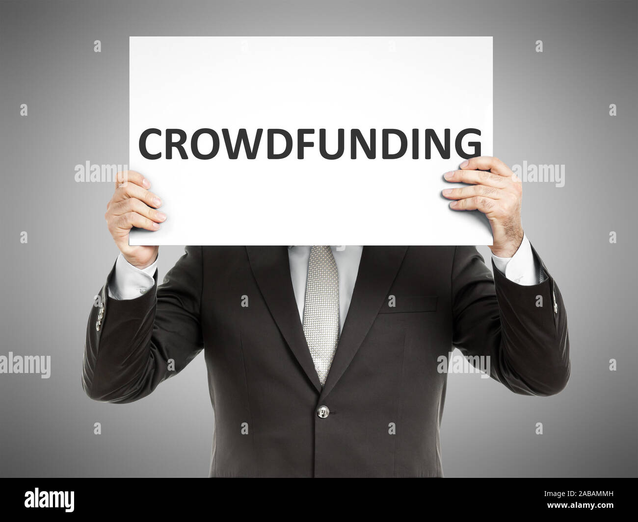 Ein Geschaeftsmann, der ein Schild mit den Worten 'Crowdfunding' in der Hand haelt Stock Photo