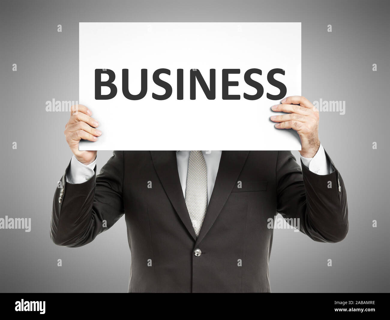 Ein Geschaeftsmann, der ein Schild mit den Worten 'Business' in der Hand haelt Stock Photo