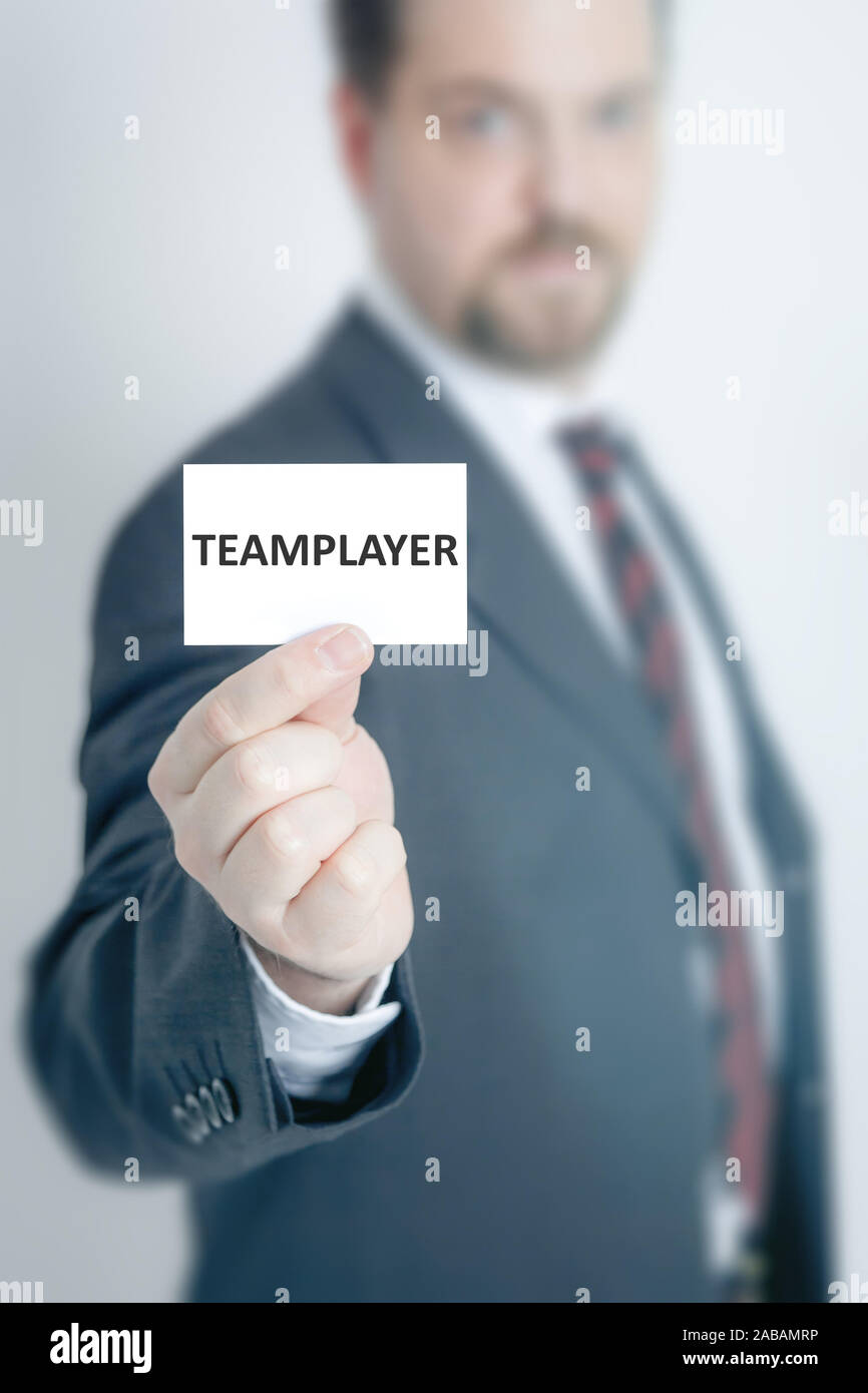 Ein Geschaeftsmann, der eine Visitenkarte mit den Worten 'Teamplayer' in der Hand haelt Stock Photo