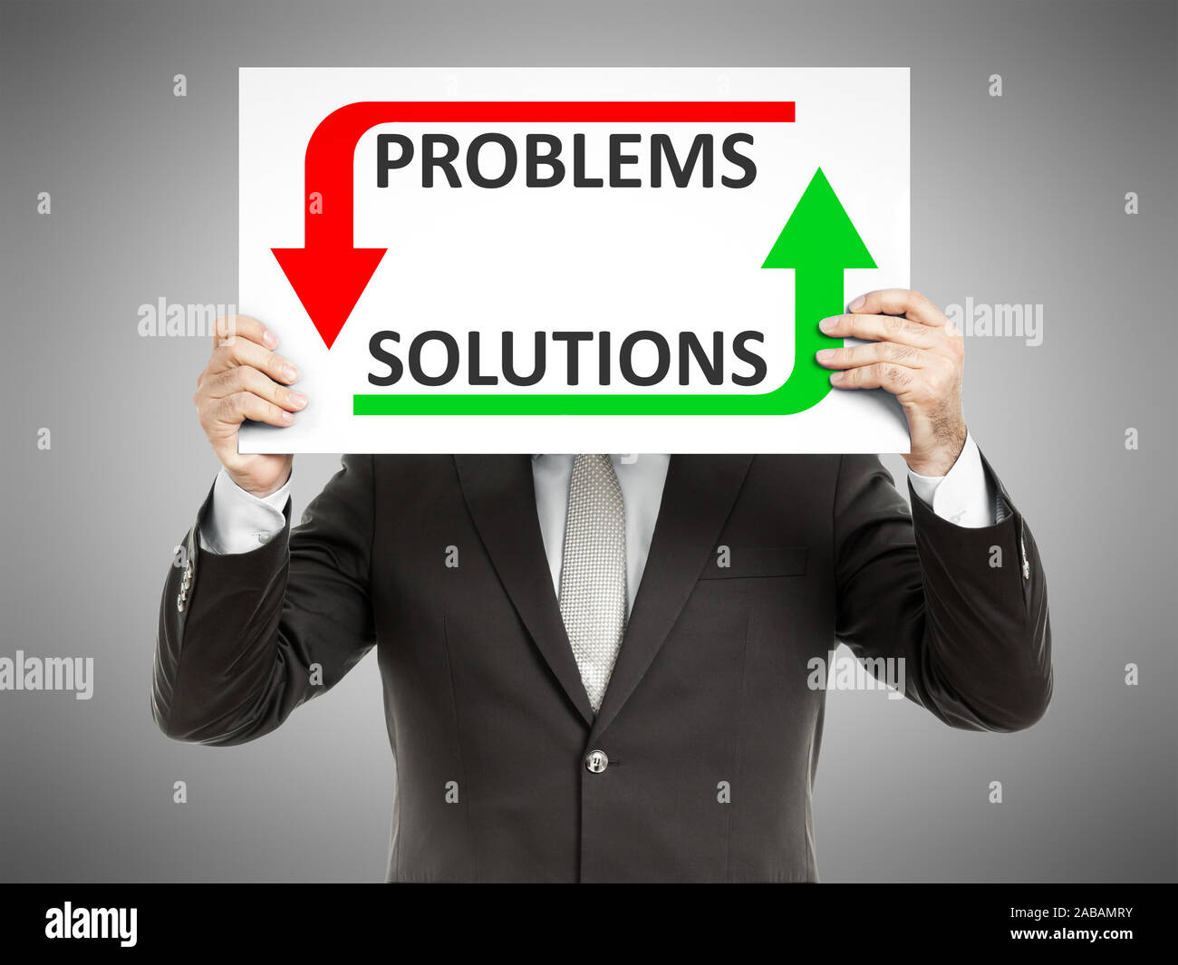 Ein Geschaeftsmann, der ein Schild mit den Worten 'Problems Solutions' haelt Stock Photo