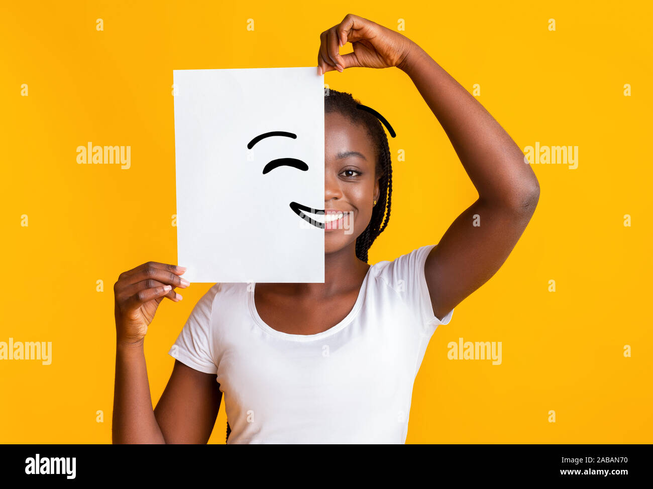 Black woman covering half face with smiley picture Stock Photo