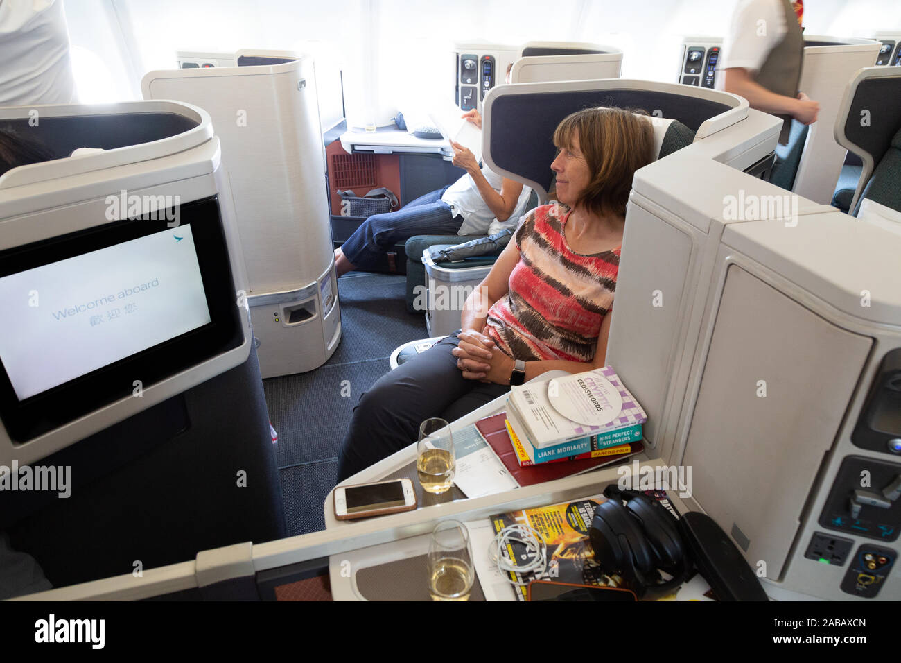 Business class travel; A woman passenger sitting in Cathay Pacific business class cabin on a Cathay Pacific plane flight from Australia to Hong Kong Stock Photo