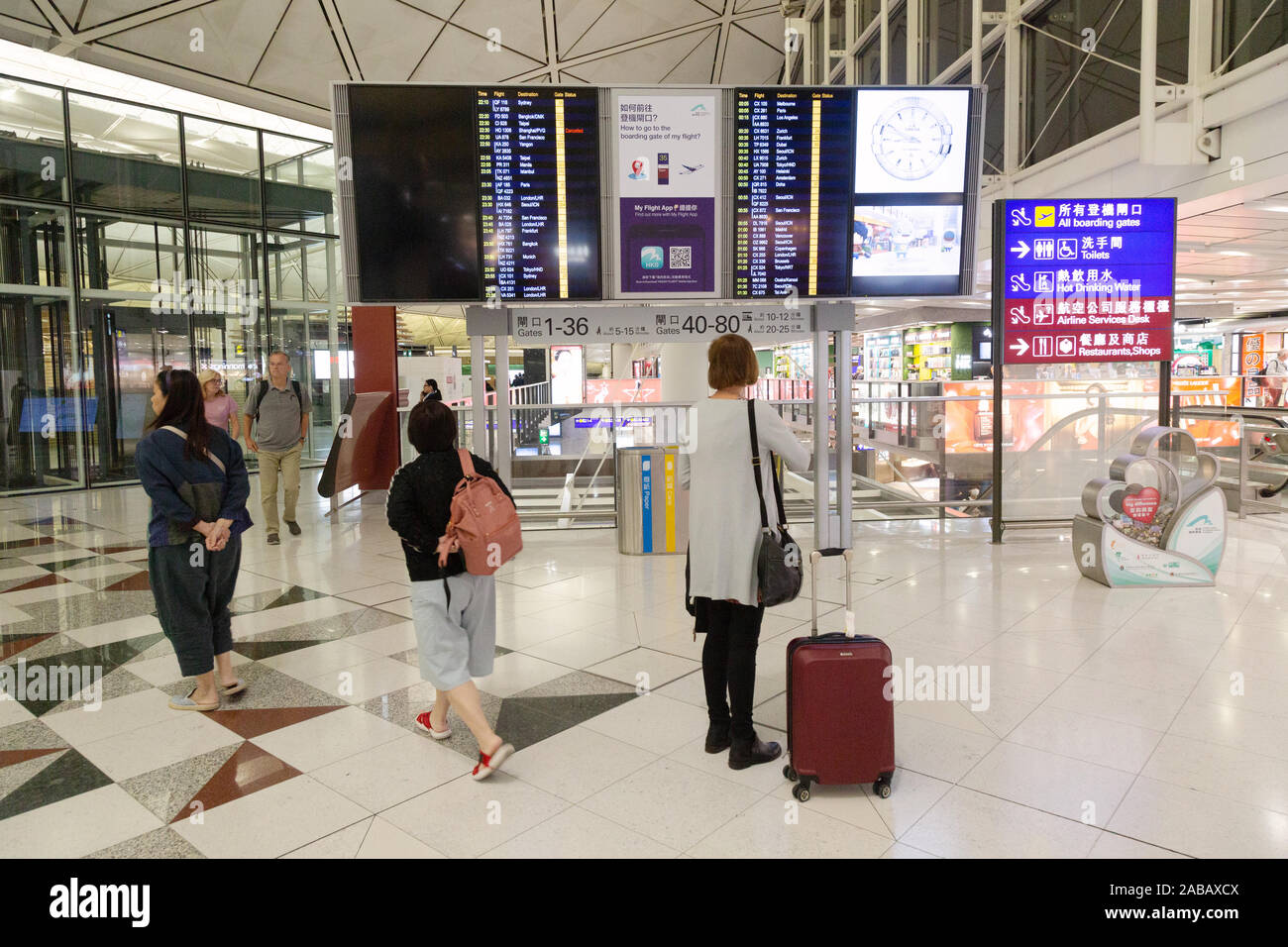 Passengers looking at the flight departure board in the terminal interior. Hong  Kong International Airport, Hong Kong Stock Photo - Alamy