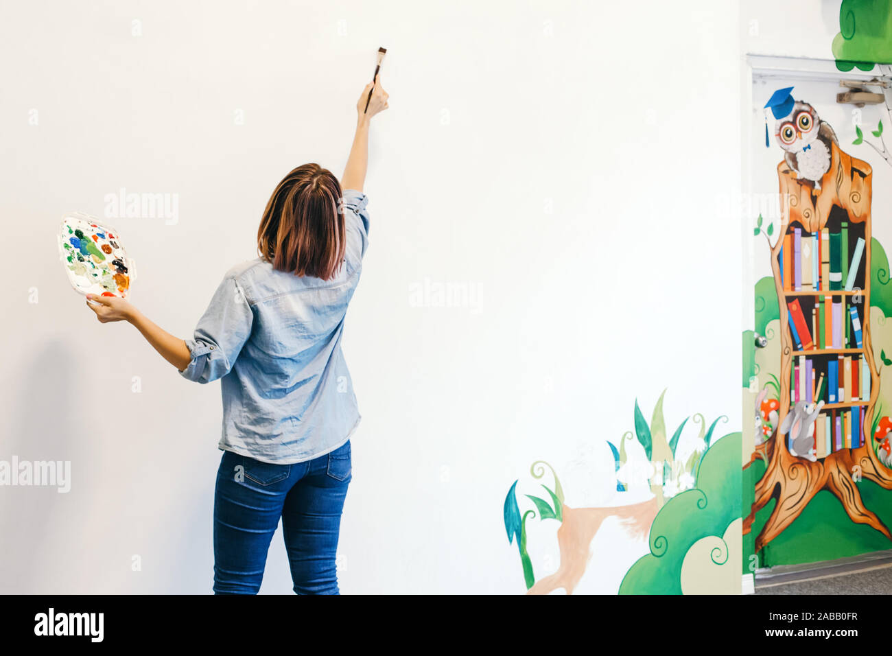 Lifestyle creative hobby and freelance artistic work side job concept. Caucasian woman artist hand painting murals on walls indoor at apartment or stu Stock Photo