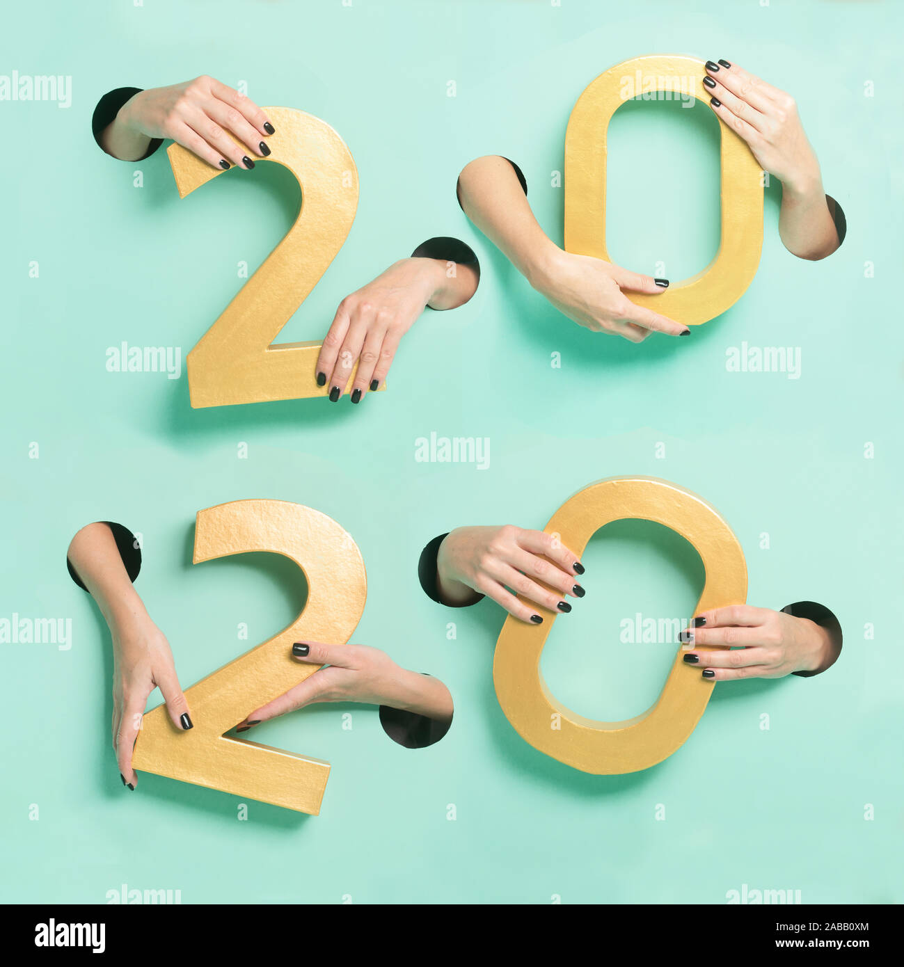 Female hands hold golden new year 2020 digits through a hole on neon mint background. Stock Photo