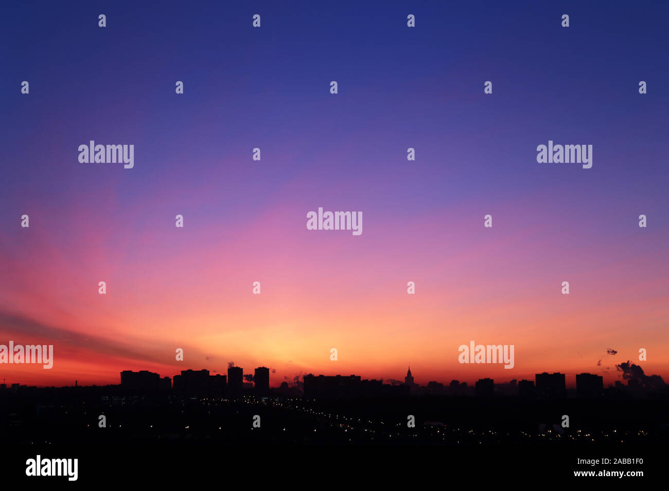 Sunrise over the city, scenic view. Pink-blue sky and cirrus clouds in soft colors above black silhouettes of high-rise buildings, colorful cityscape Stock Photo