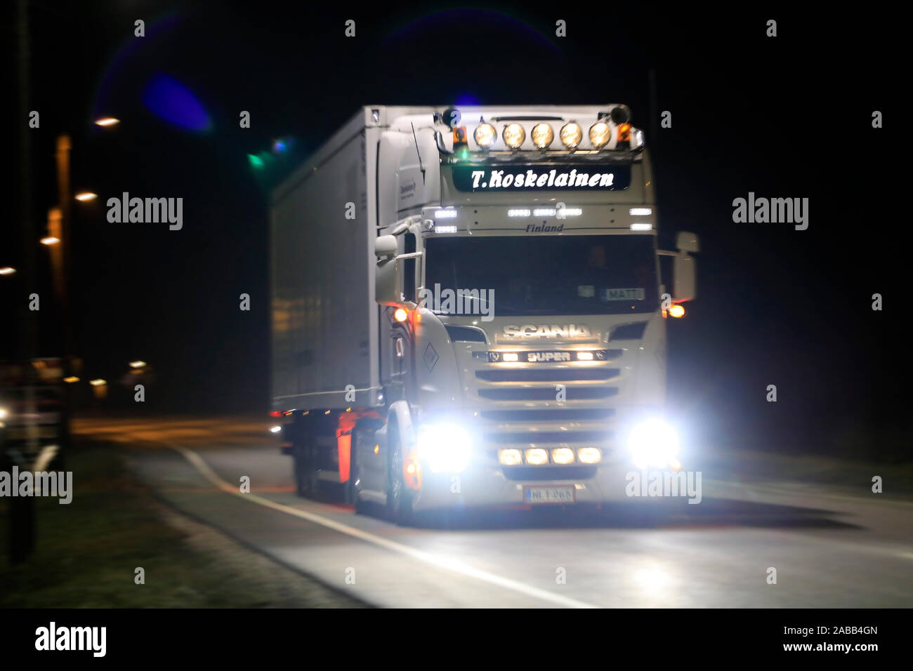 Customised Scania truck in front of trailer lights up the dark road with bright headlights. Vehicle at speed, motion blur. Salo, Finland. Nov 22, 2019 Stock Photo