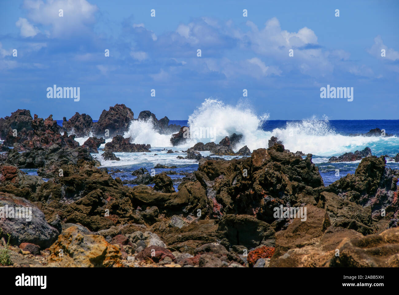 Blue ocean (sea) and white waves breaking on rocks on the rocky shoreline of Easter Island. Stock Photo