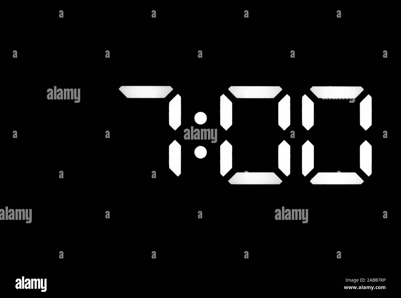 Real white led digital clock on a black background showing time 7:00 Stock Photo
