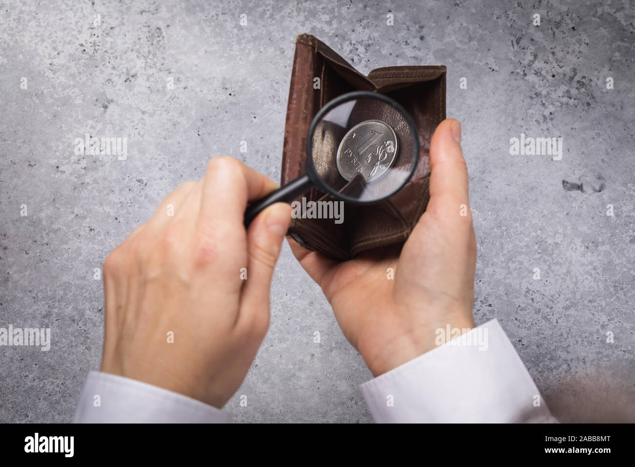Russian ruble in a wallet. A man is looking for money in a wallet with a magnifying glass. The concept of poverty, top view Stock Photo