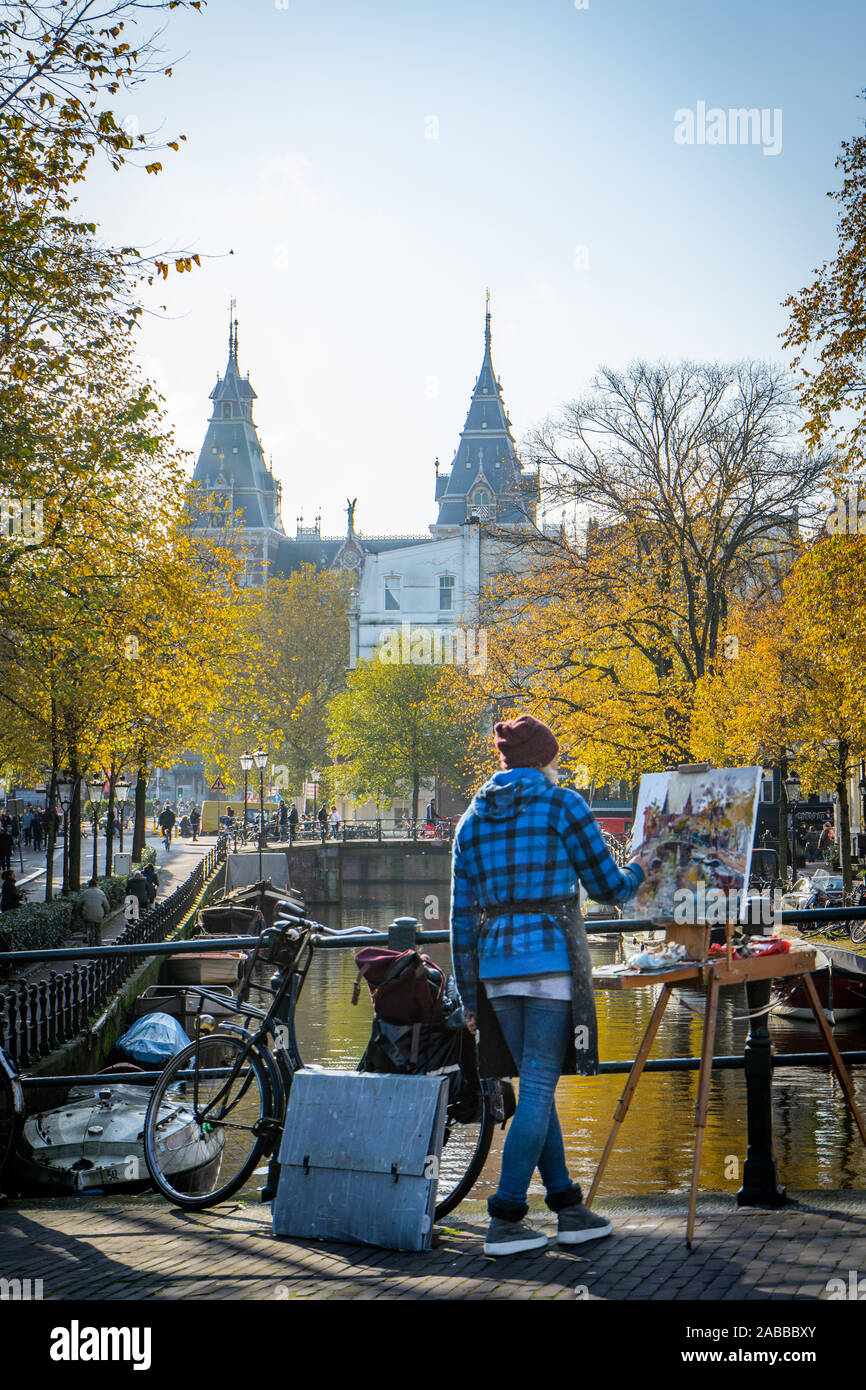 Artist painting on canvas in the streets of Amsterdam surrounded by