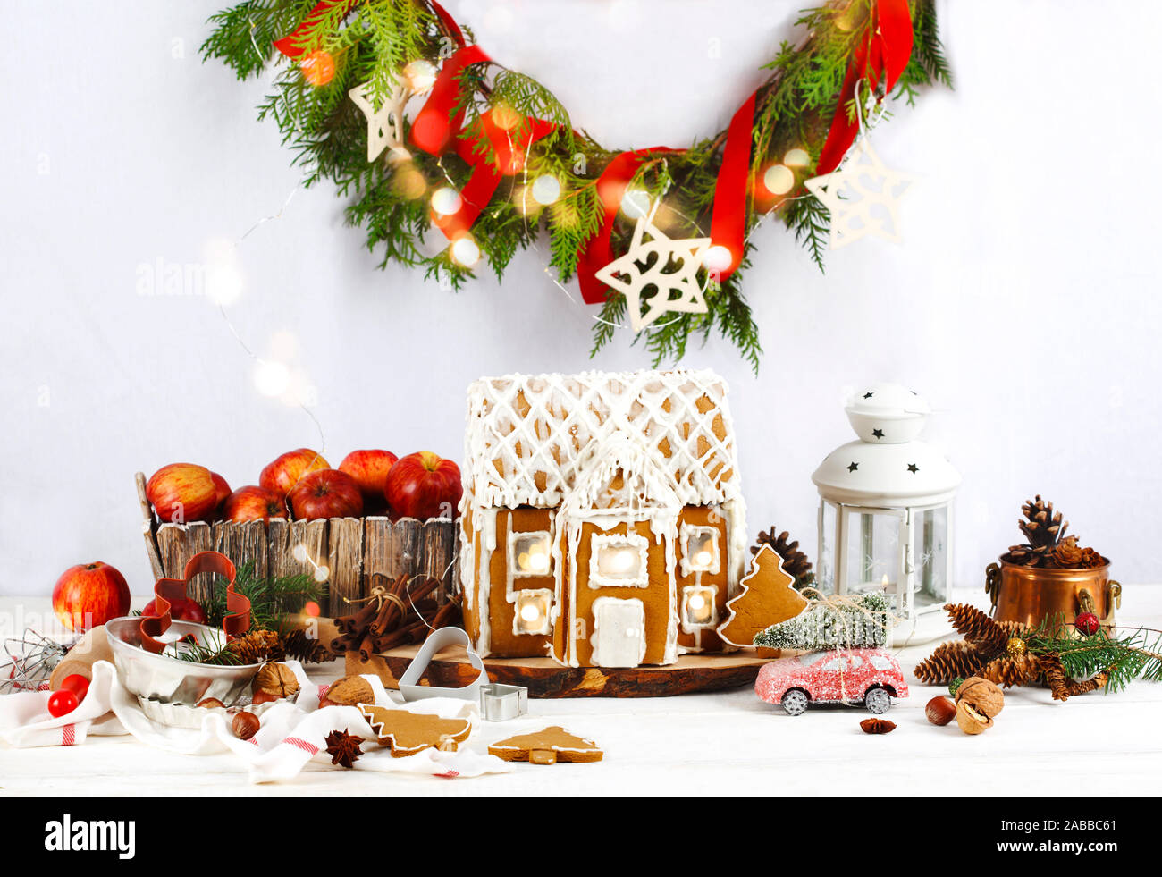 Gingerbread house on wooden table with a wreath and holiday decorations Stock Photo
